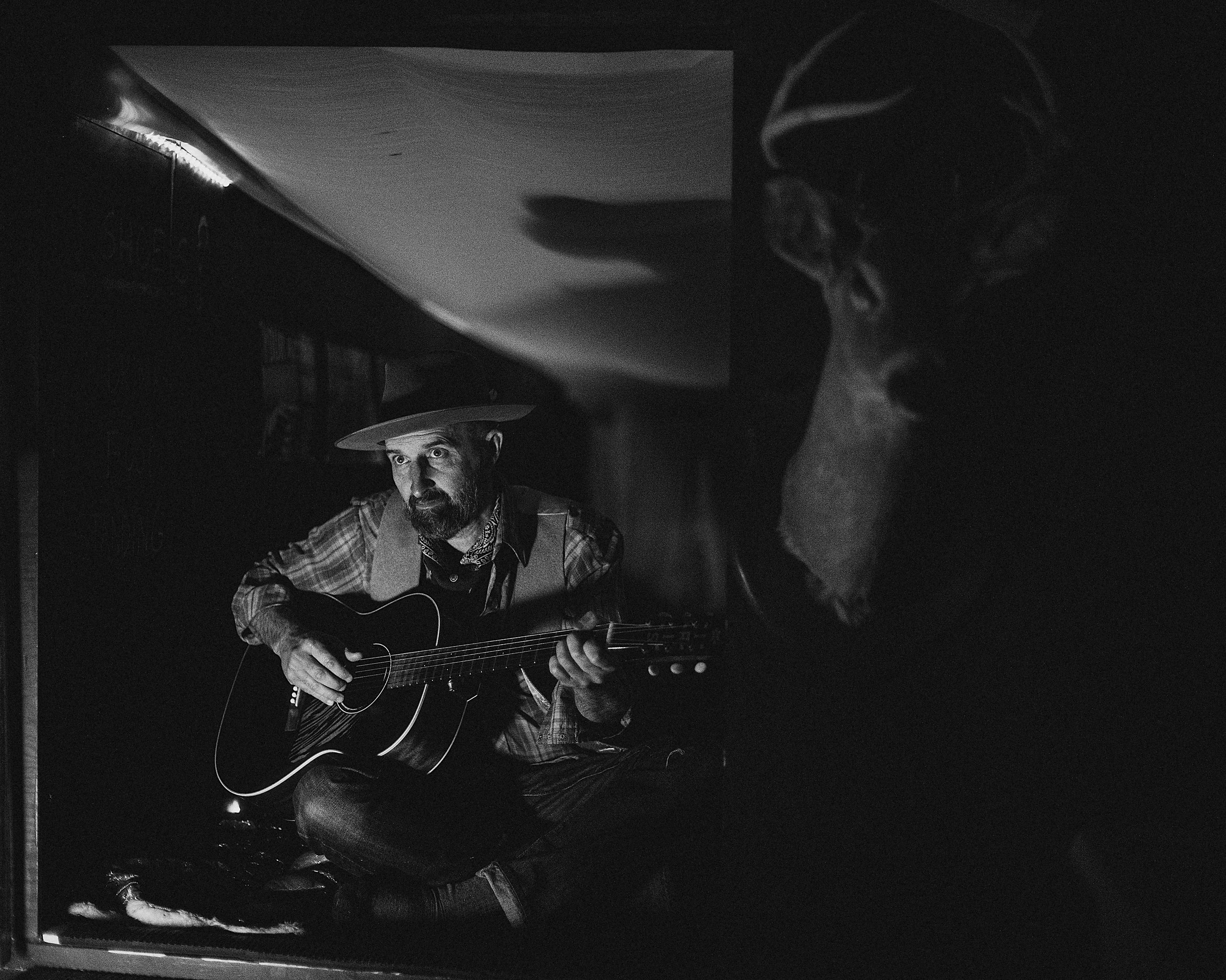 Atmospheric black and white portrait of blues singer-songwriter Seth Walker playing acoustic guitar, photographed by Parker J. Pfister.