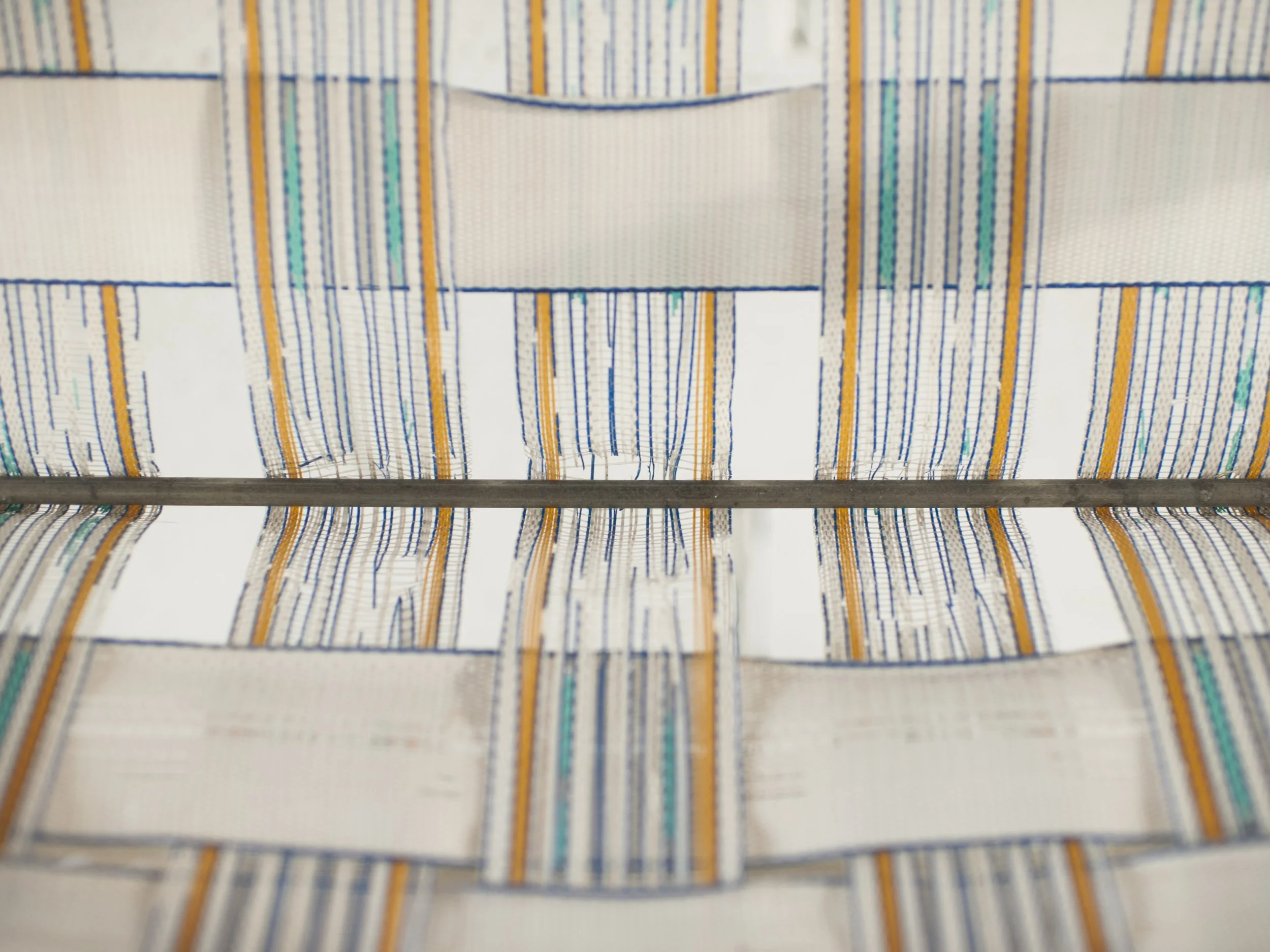 A textured, close-up color film photograph focusing on the blue, white, and orange patterned straps of a vintage woven lawn chair, from the One Way Out, Lord series by Parker J Pfister.