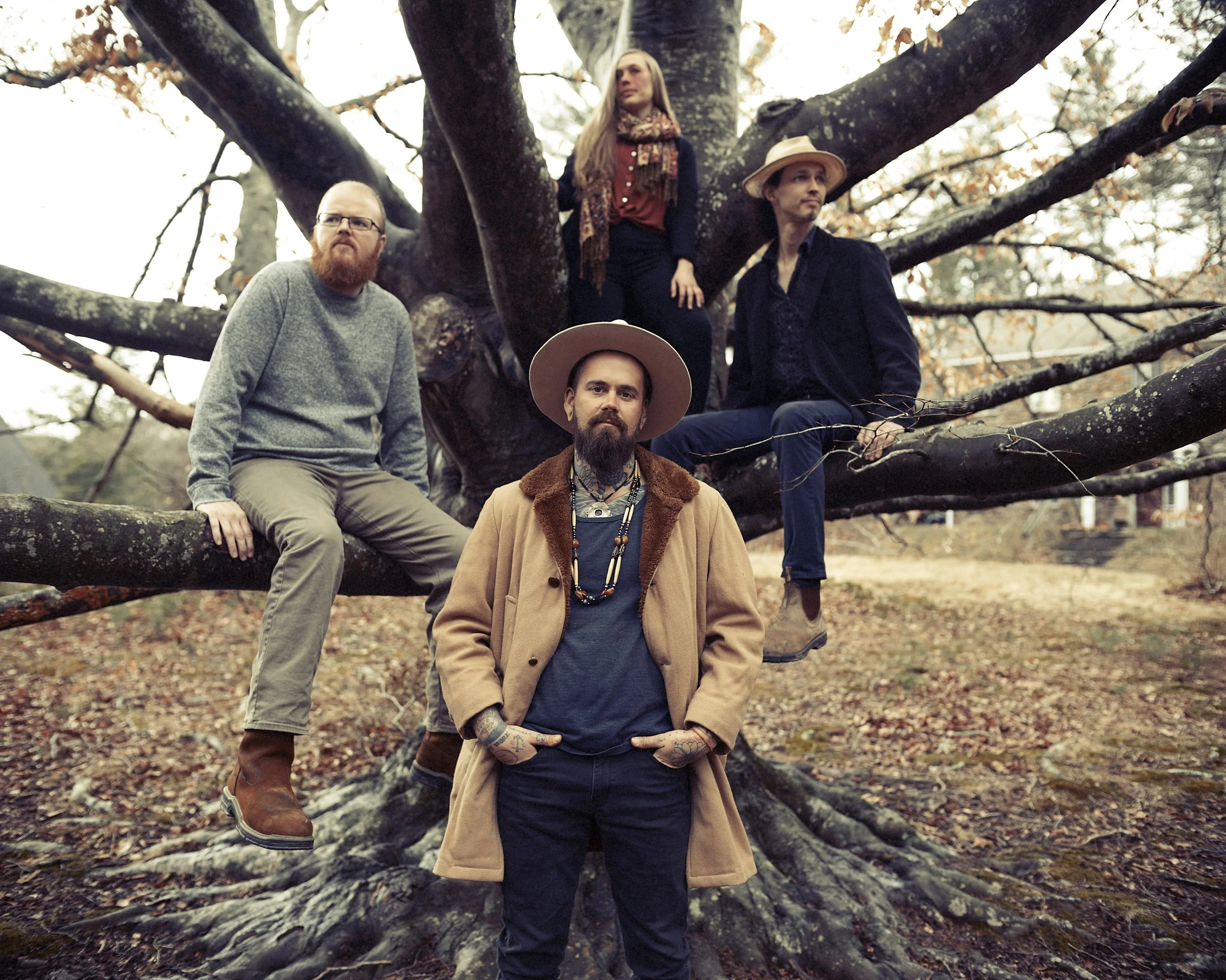 Group portrait of Western North Carolina acoustic band Life Like Water gathered outdoors beneath a massive sprawling oak tree, photographed by Parker J. Pfister.
