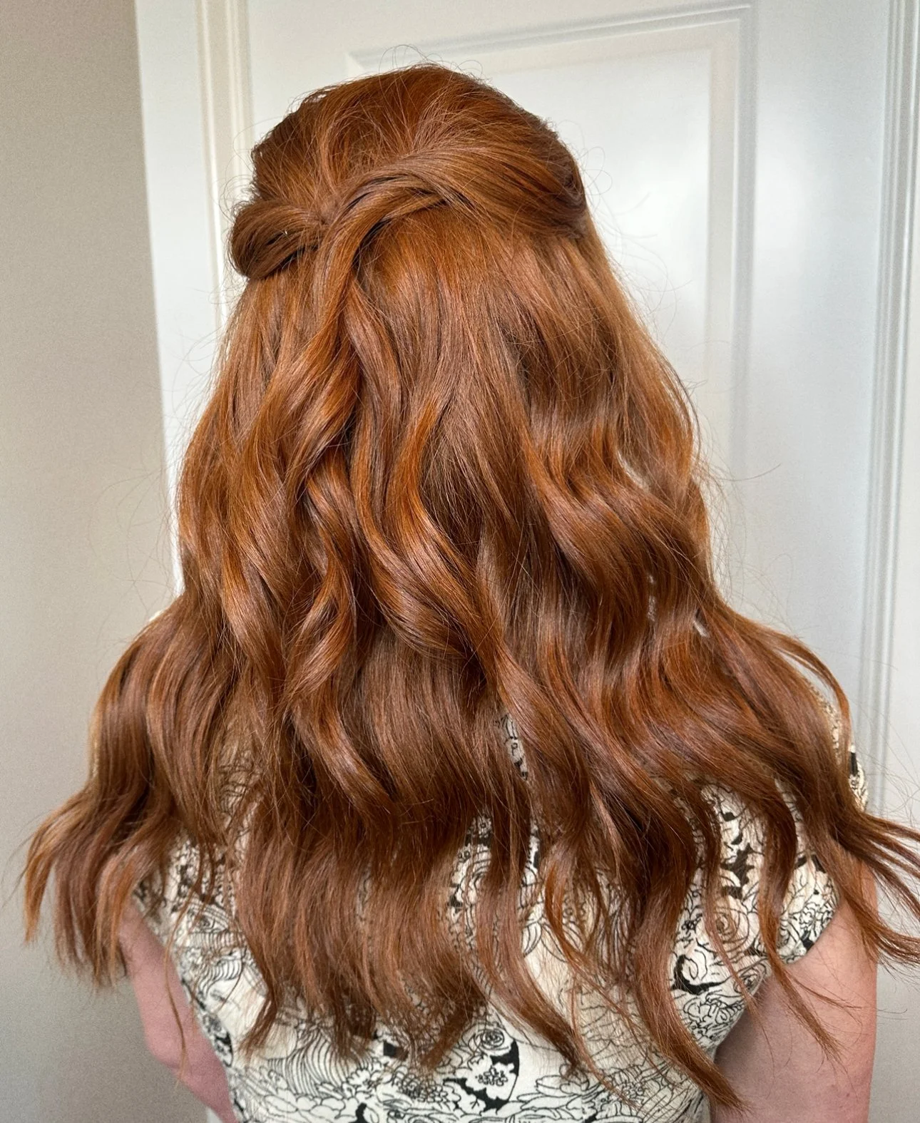 Back view of a woman with long, wavy, red hair.