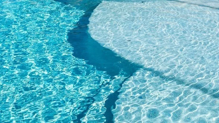 Close-up of a swimming pool with clear blue water and visible pool steps.