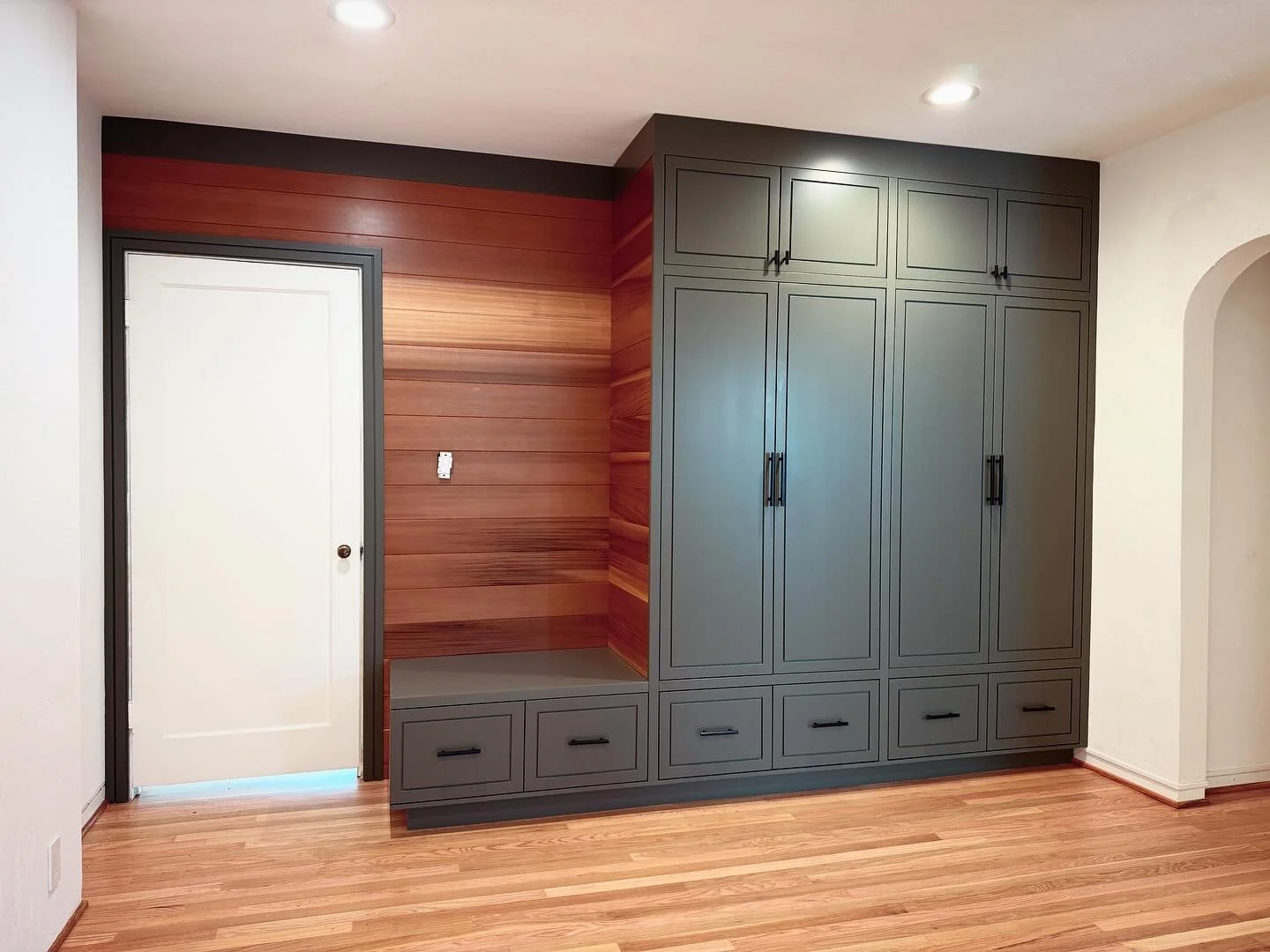Multifunction living room built-in. Floor to ceiling paint grade face frame casework with custom slab door detail. Clear western red cedar v-groove shiplap and matching door casing.