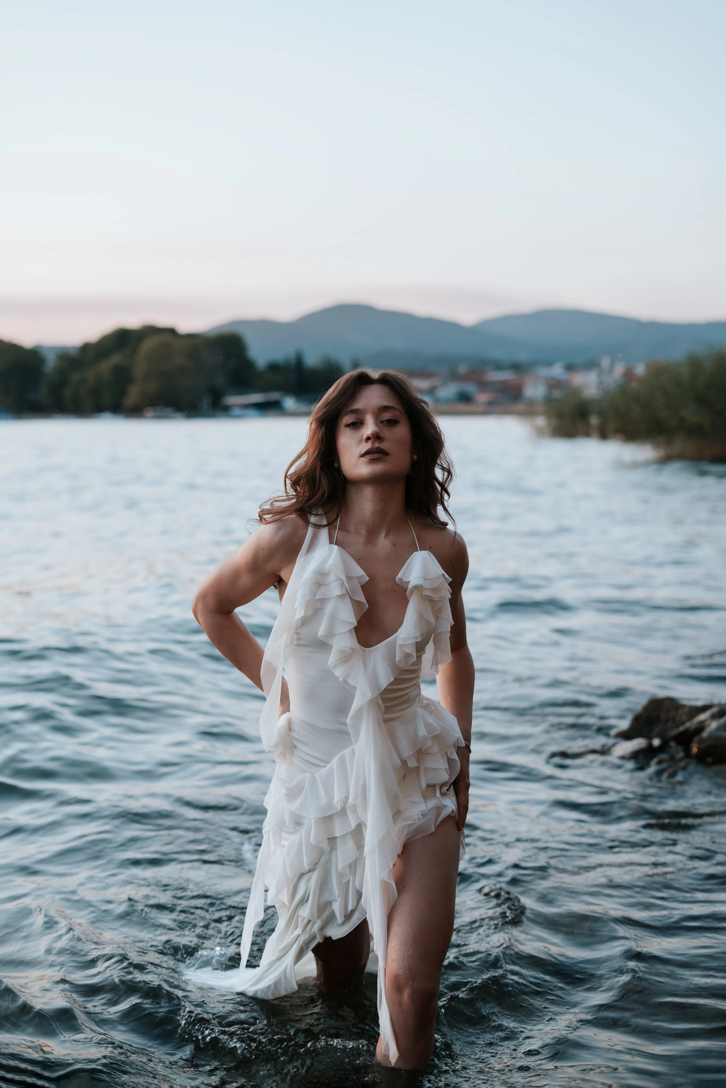 A portrait photograph of a beautiful woman in a white dress getting out of the lake, wet dress and elegant posture. Captured by a female photographer from Slovenia, Hristina Trajkoska - HTR studio