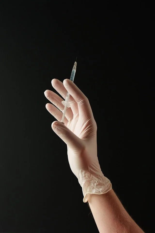 hand met botox spuit tegen een zwarte achtergrond