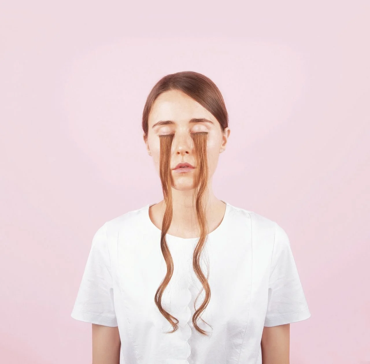 Vrouw met haar voor haar ogen, roze achtergrond.