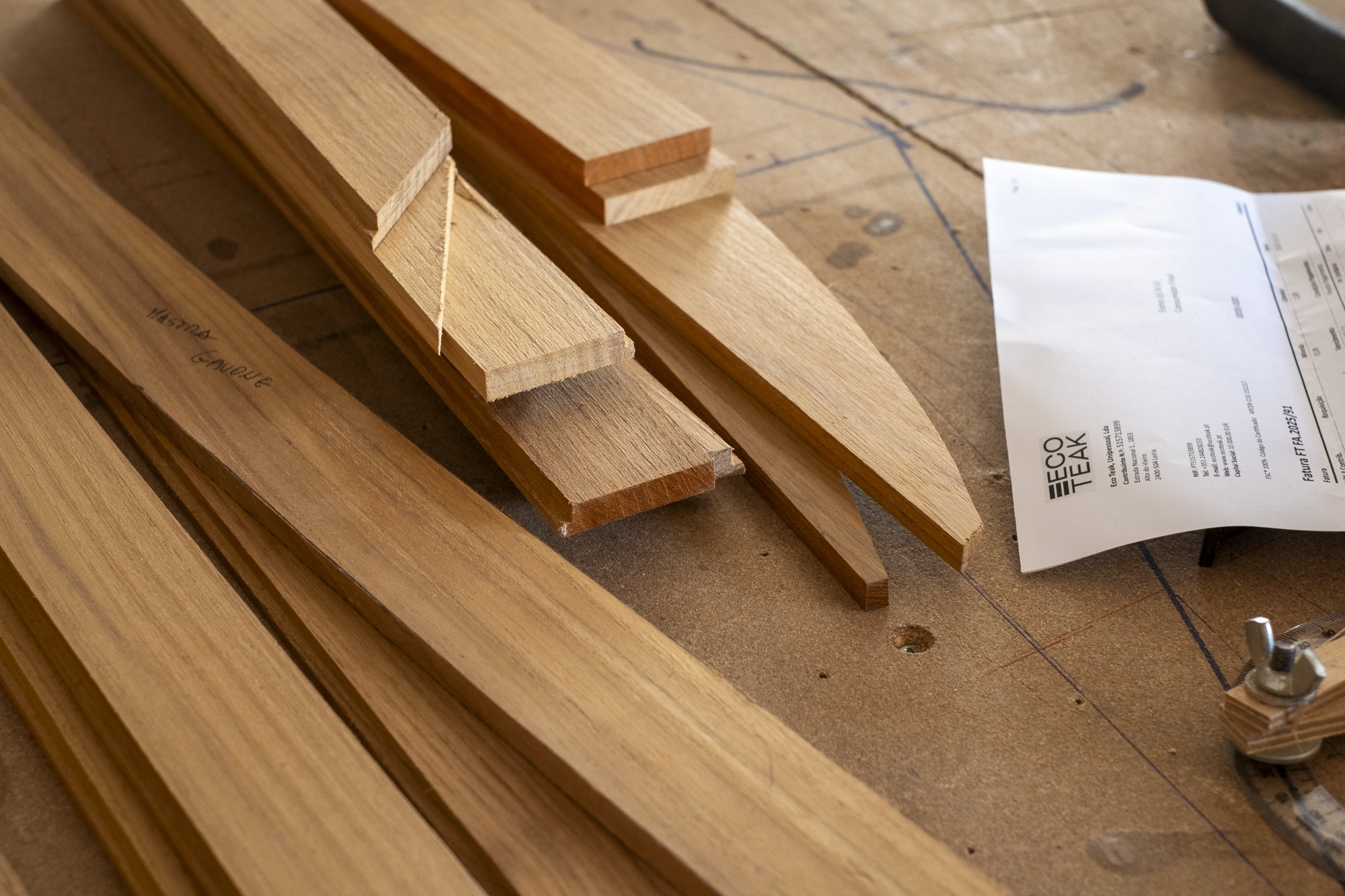 Various wooden planks and pieces on a workbench, with a paper receipt or instructions nearby.