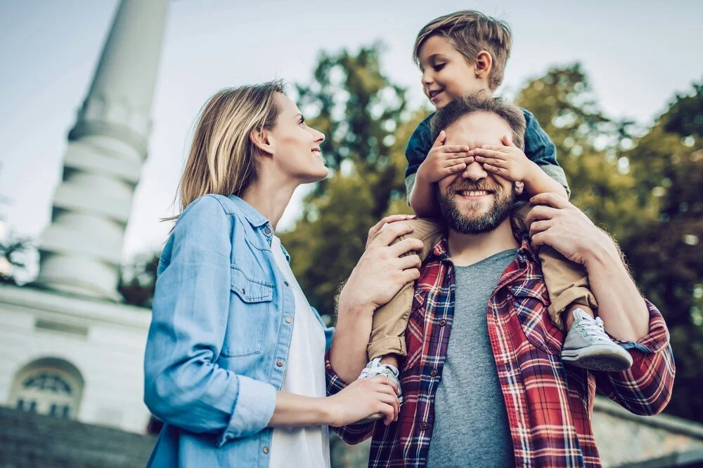 Smiling family with a young child outside a church building, reflecting warmth, belonging and a family-centred church community.