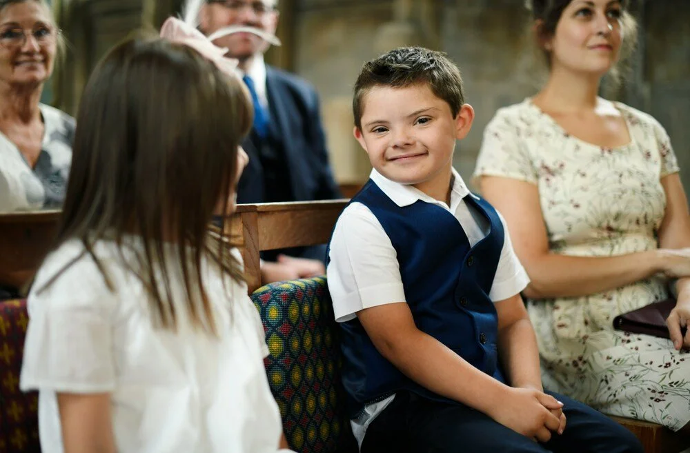 Young boy sitting in church beside family members, smiling during a church service.