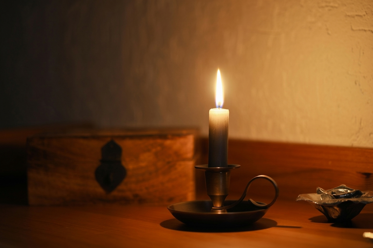 Lit candle glowing in a dark room symbolizing the light of Christ and hope in Easter