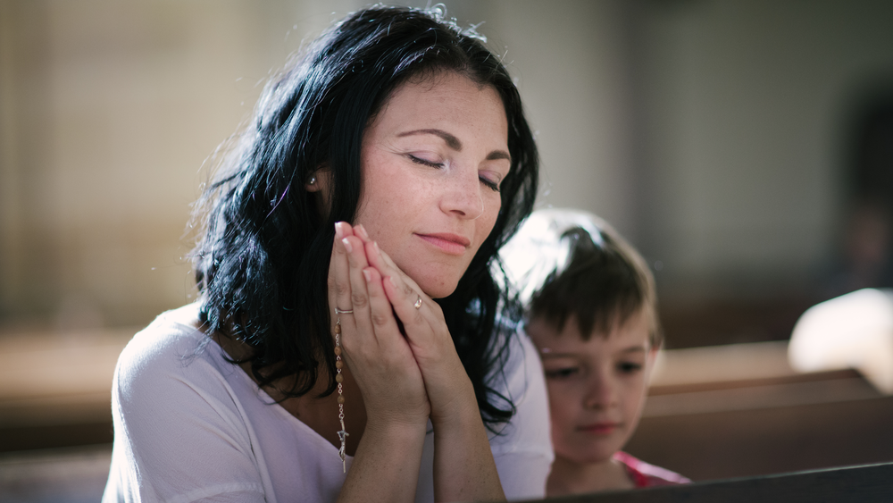 Woman praying in church while exploring faith, worship, and finding the right Christian church community.
