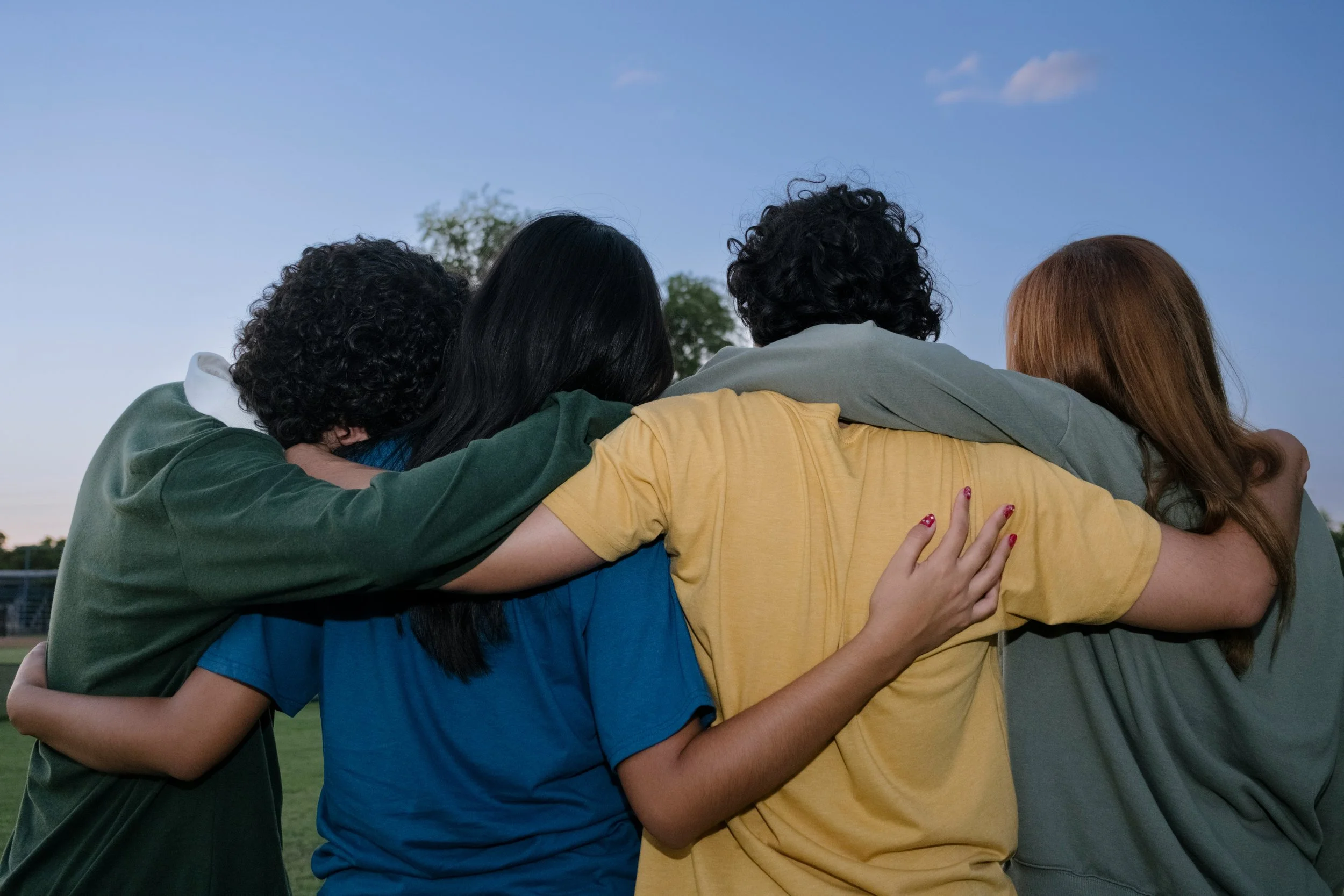 Young adults standing together with their arms around one another