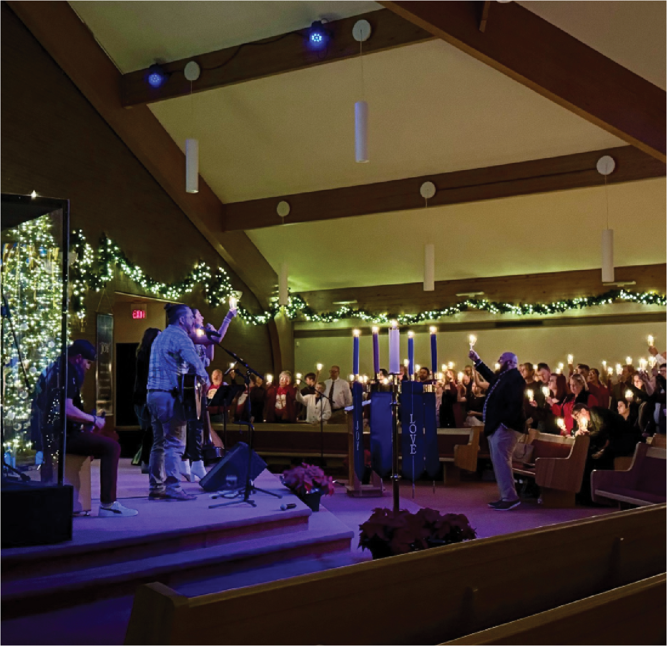 Cross standing in a field at sunrise with a lamb grazing nearby