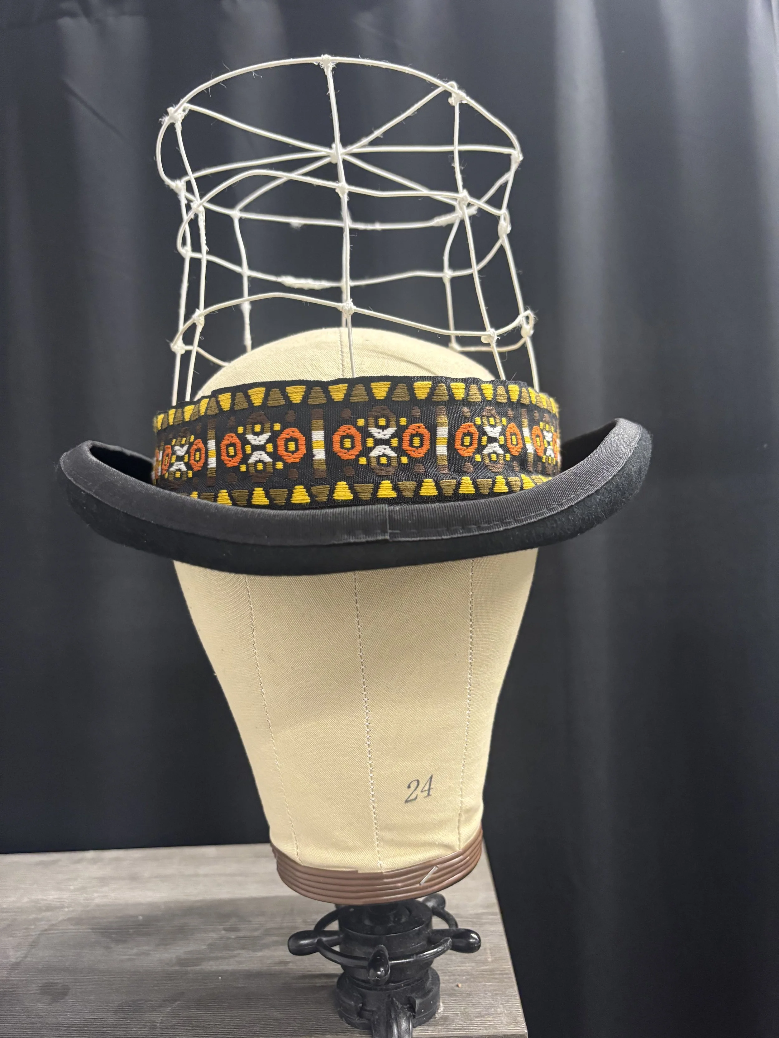 (Hat #1) Top hat base with crown removed. Crown sculpted with millinery wire and secured. Ribbon used for hatband.