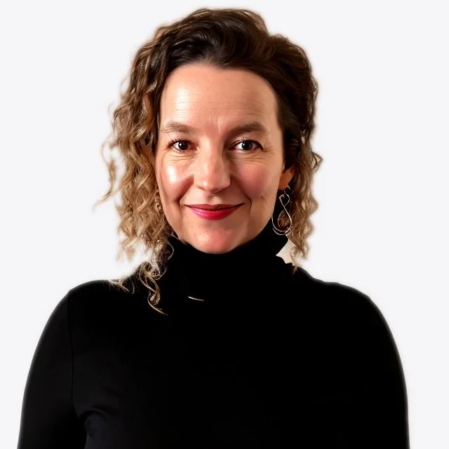 A woman with curly brown hair wearing a black turtleneck sweater and a dangling earring, smiling at the camera against a plain white background.
