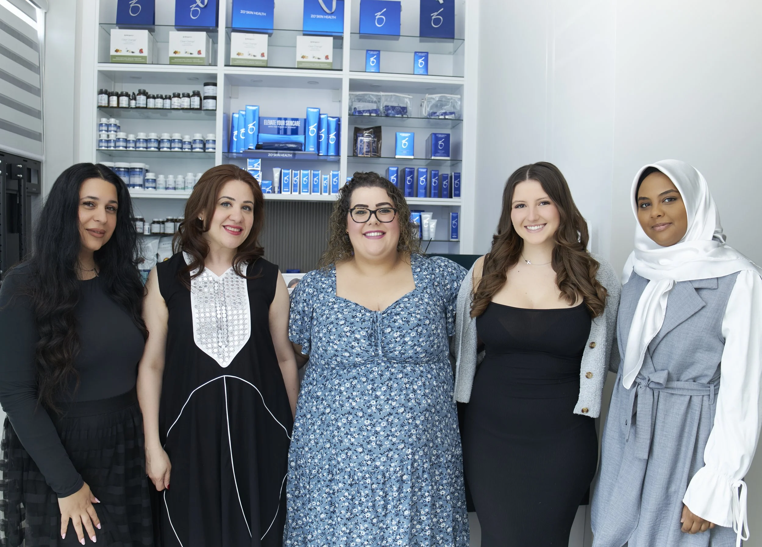 Group of five women standing in front of shelves with health and skincare products, smiling for the photo.