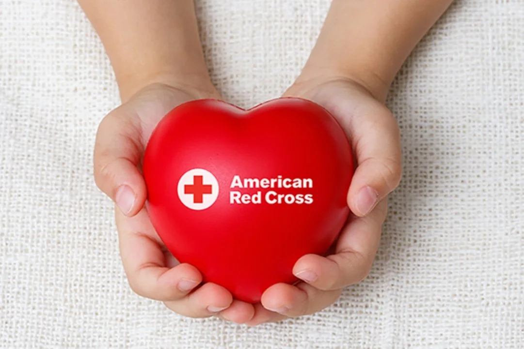 hands holding a red cross toy heart
