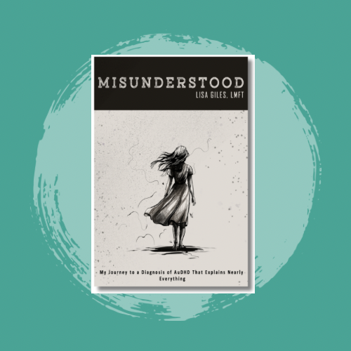 Book titled "Misunderstood" by Lisa Giles, LMFT, standing on a table with a drawing of a girl with windblown hair on the cover, positioned near pink and orange flowers.