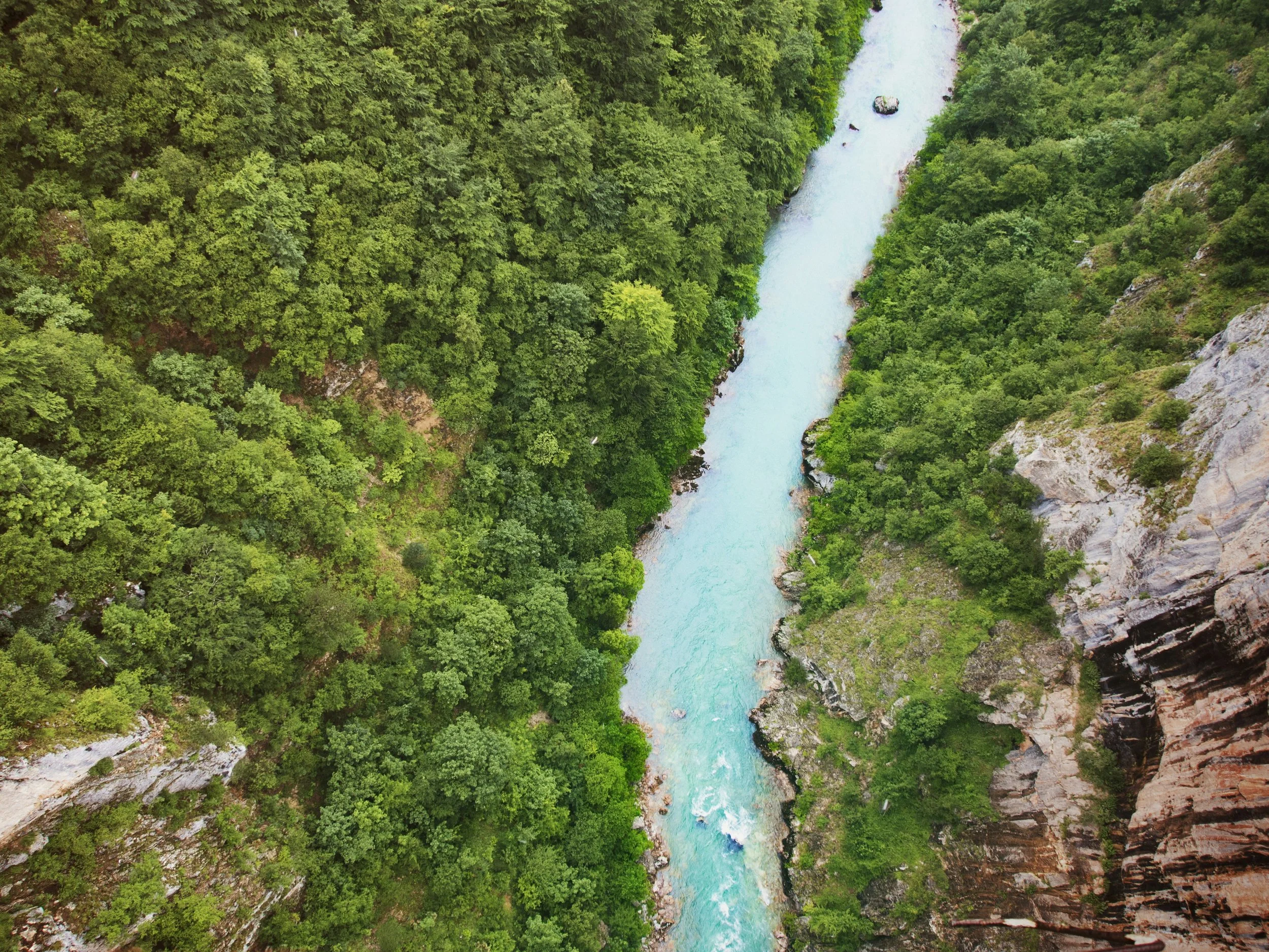 Aerial view of a river flowing through a lush green canyon with steep rocky cliffs on either side.