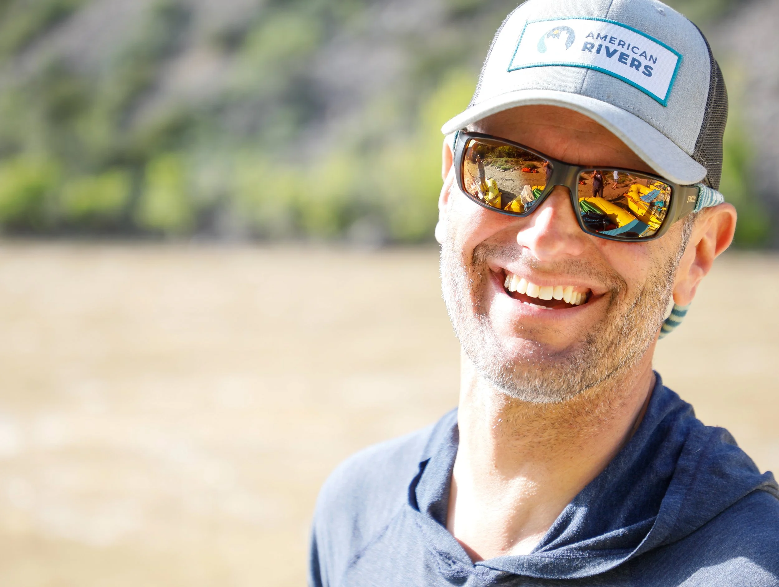 Mike is smiling and wearing a hat and sunglasses