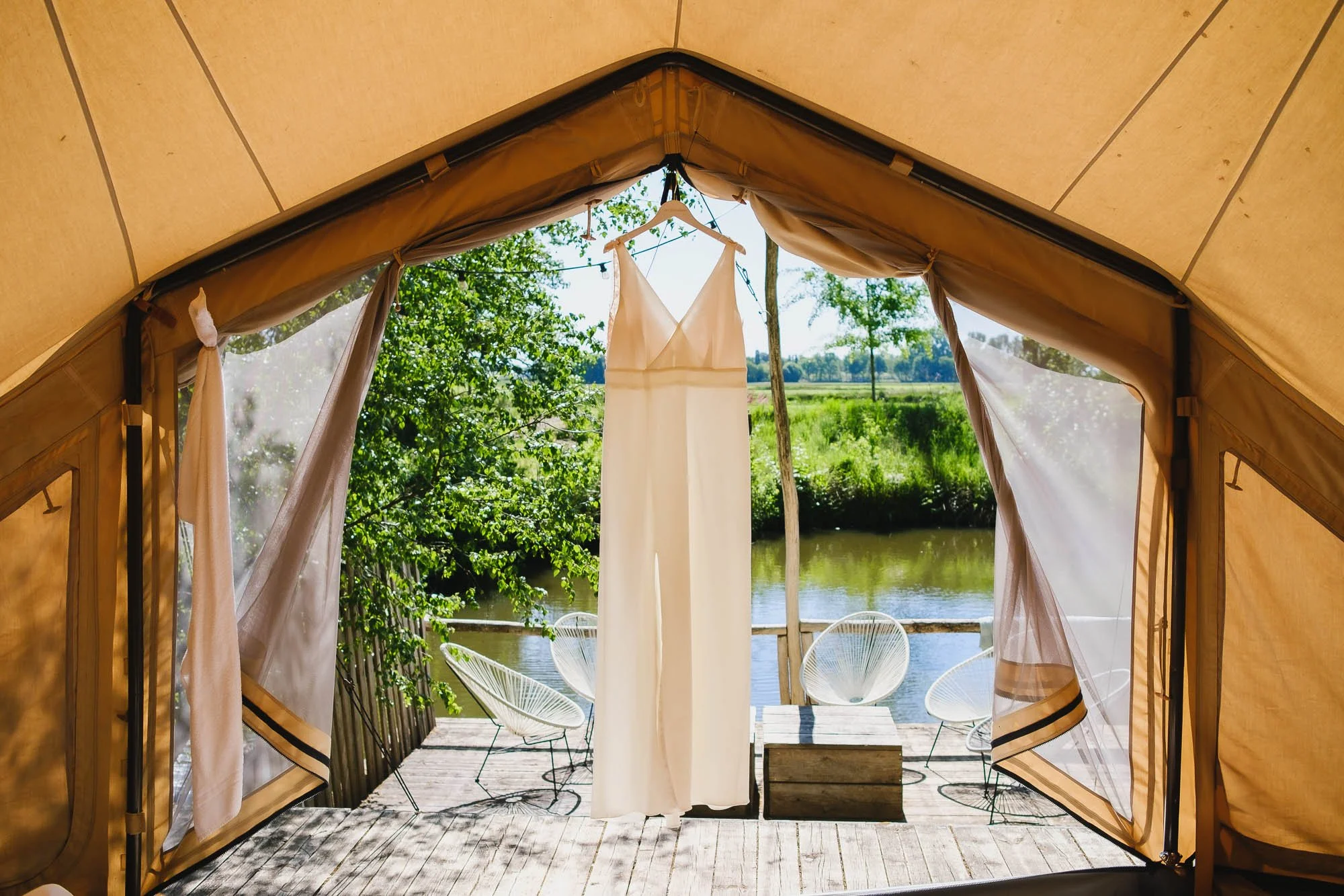 Trouwkleed van de bruid hangt klaar op een zonnige ochtend in een glampingtent in Turnhout