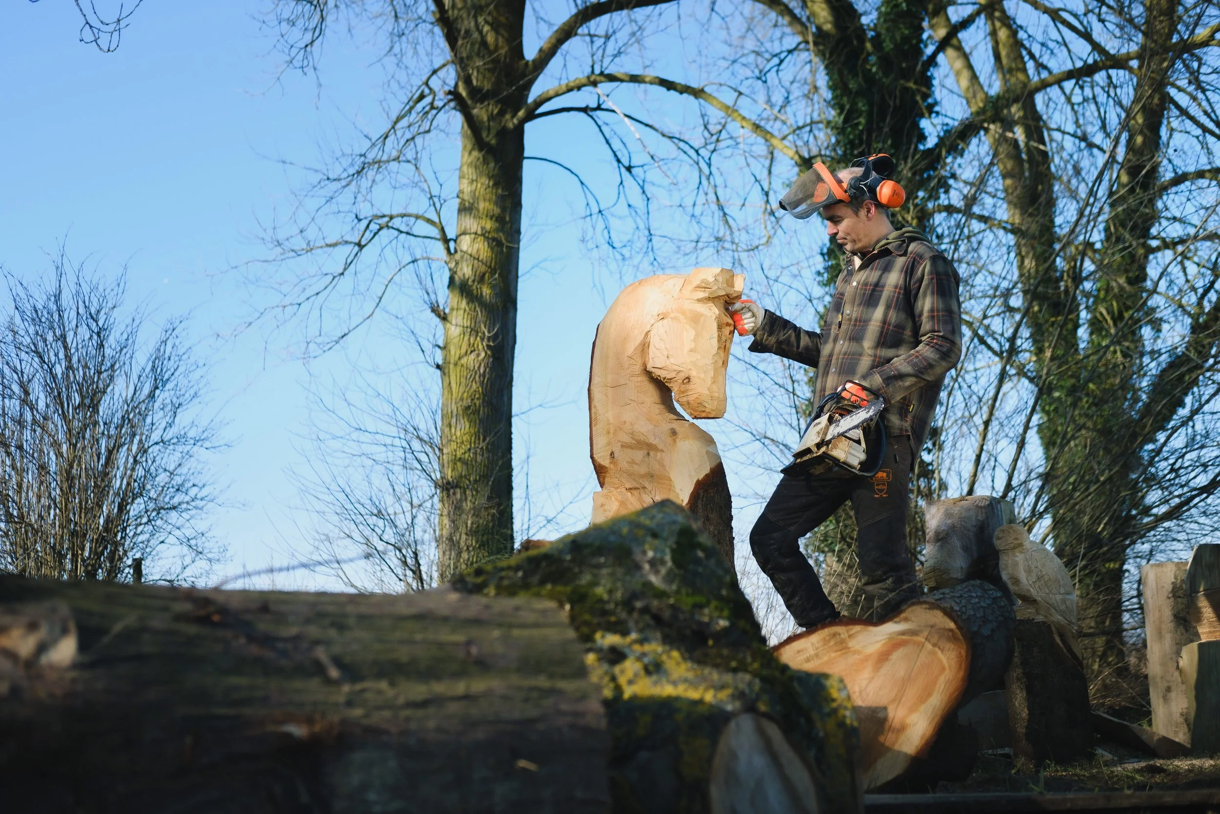 Een man kijkt naar het houten beeld van een paard dat hij met zijn kettingzaag gemaakt heeft. Hij vertelt hoe hij fan is van de koffie van Ray & Jules.