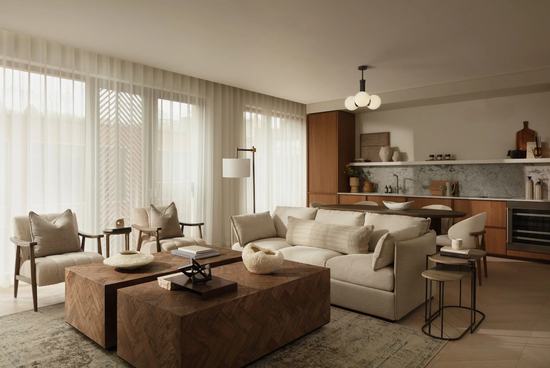 Contemporary open-plan living room and kitchen with luxury sofas, designer armchairs, oak coffee tables and bespoke cabinetry. Premium interior design and turnkey furnishing by Burbeck Interiors.