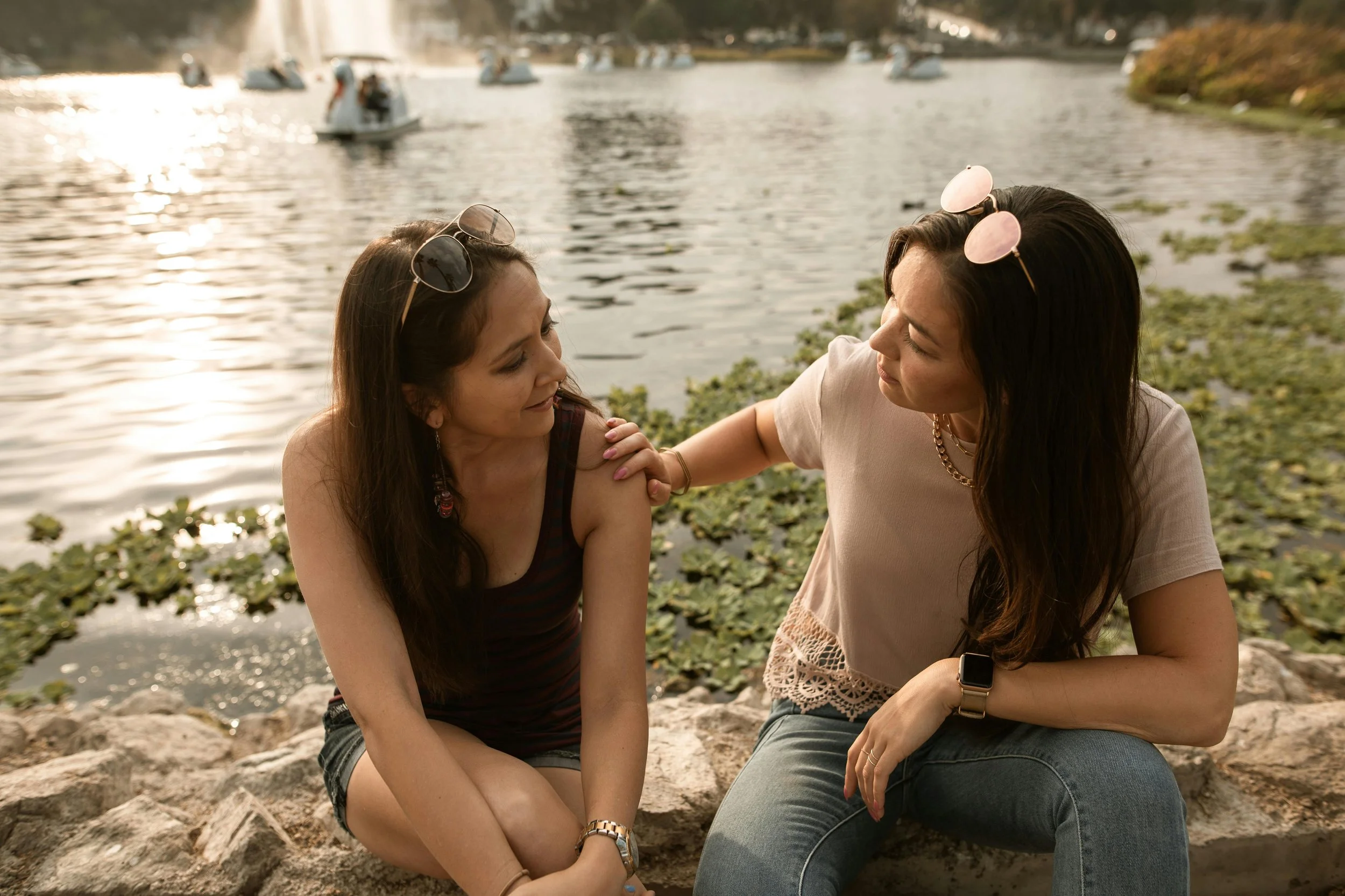 Two women talking with river background.