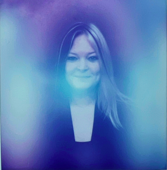 A woman surrounded by a colorful aura with purple and blue hues.