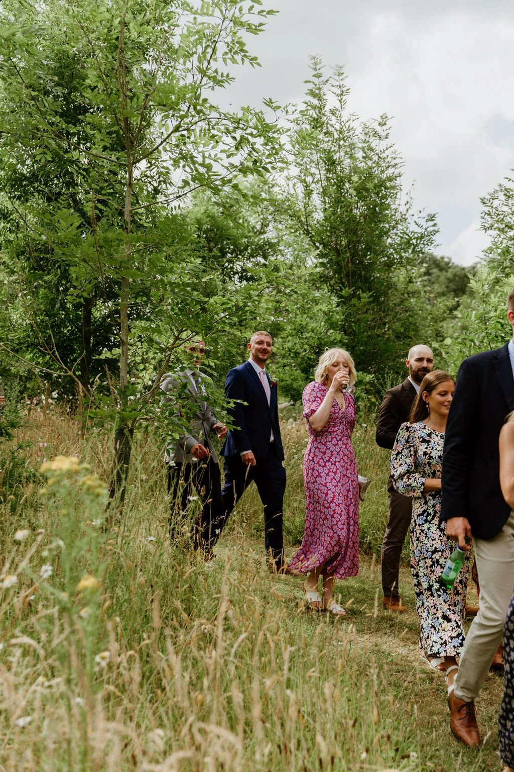 guests walk to the reception with their drinks through a beautiful meadow