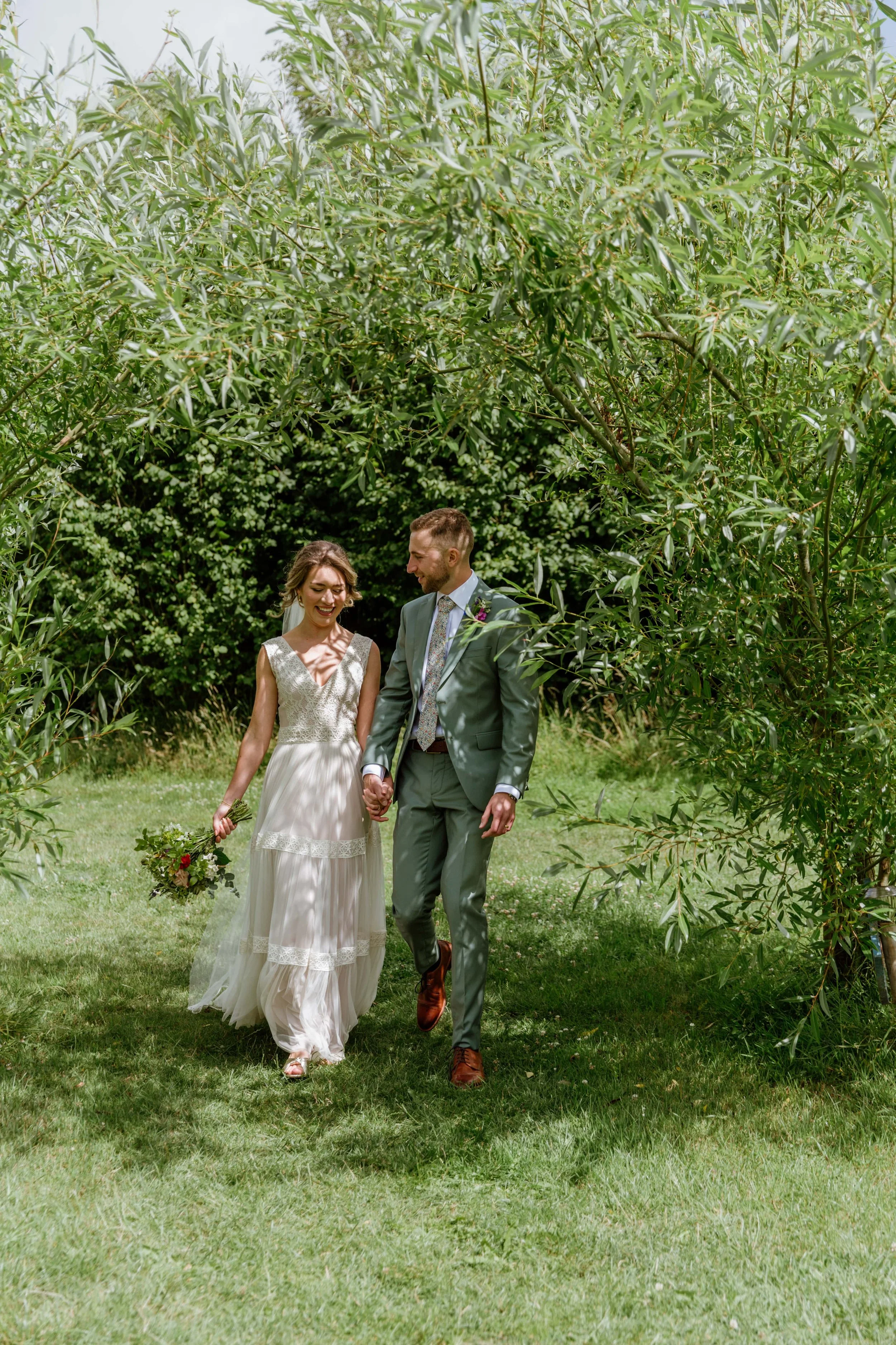 newlyweds walk under the shade of the green trees at higher holcombe in Devon
