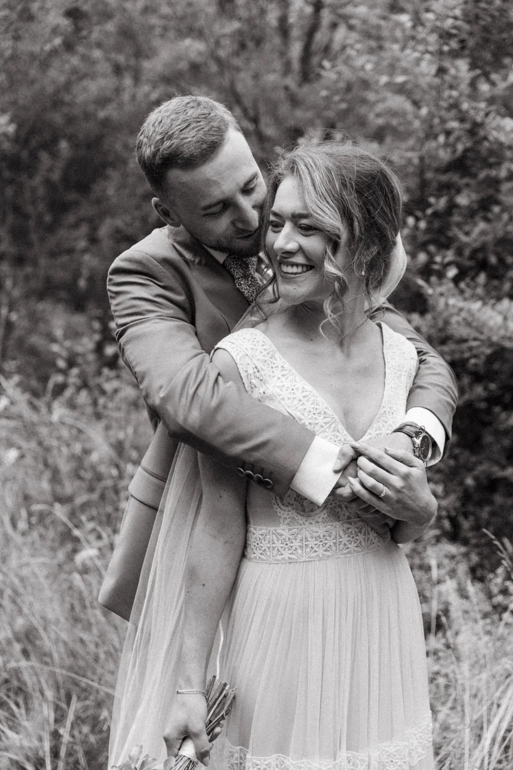 black and white image of a groom wrapping his arms around the bride