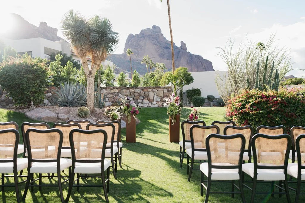 Outdoor garden setup with aisle and floral arrangements, mountainous landscape in the background