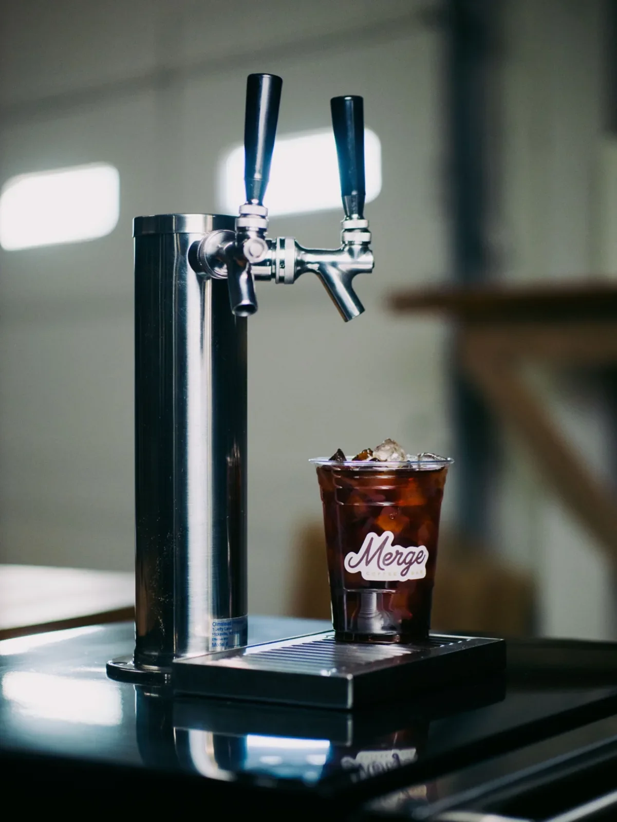 Cold brew on tap station with stainless draft tower and a Merge Coffee Bar iced cold brew cup