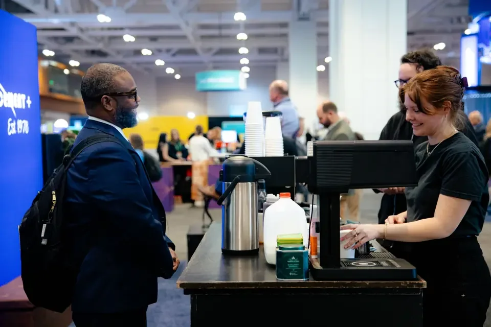Barista serving espresso at a conference expo coffee station for high-volume attendee rushes