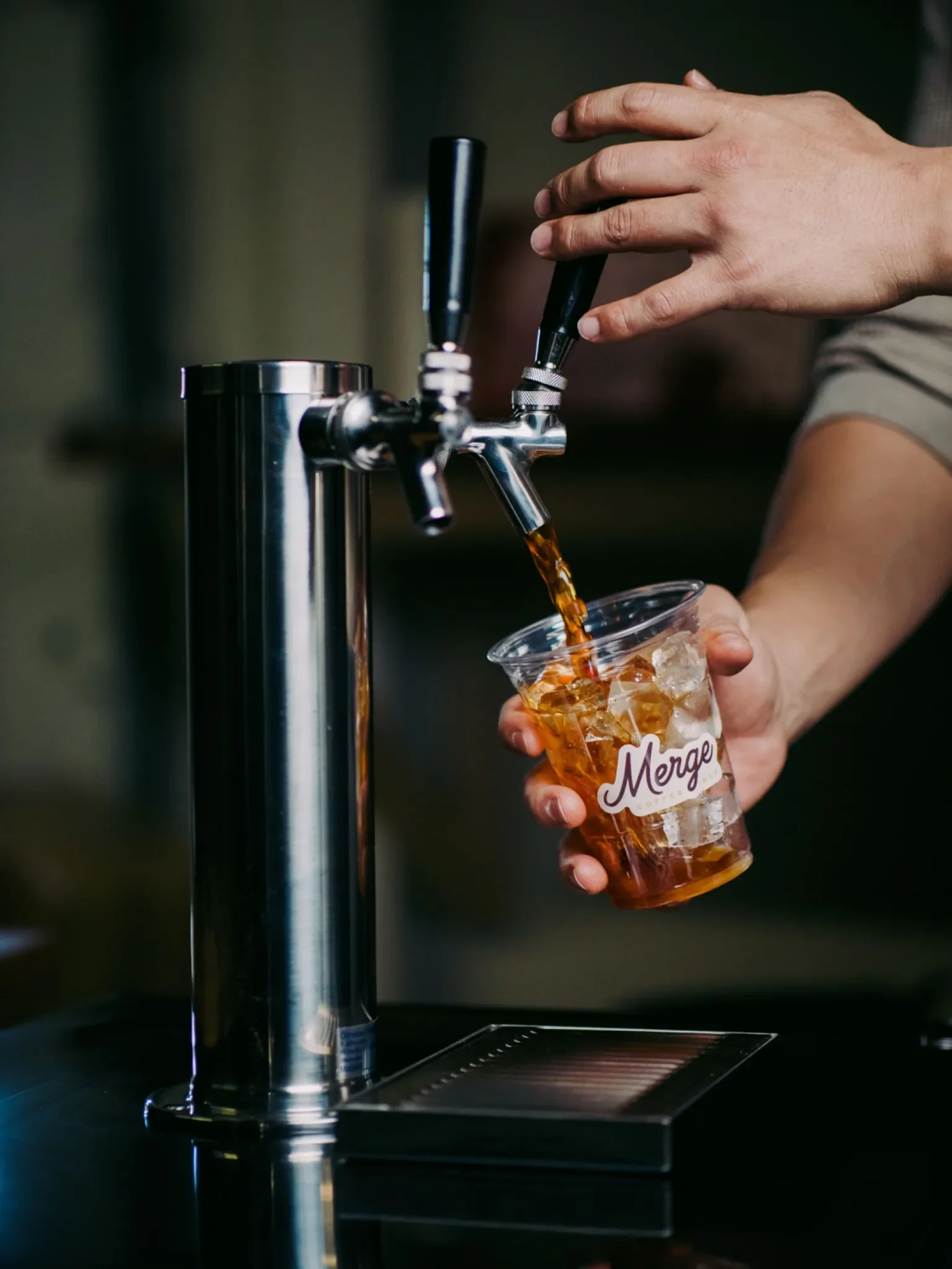 Cold brew pouring from tap into an iced cup at a Nashville coffee catering setup by Merge Coffee Bar