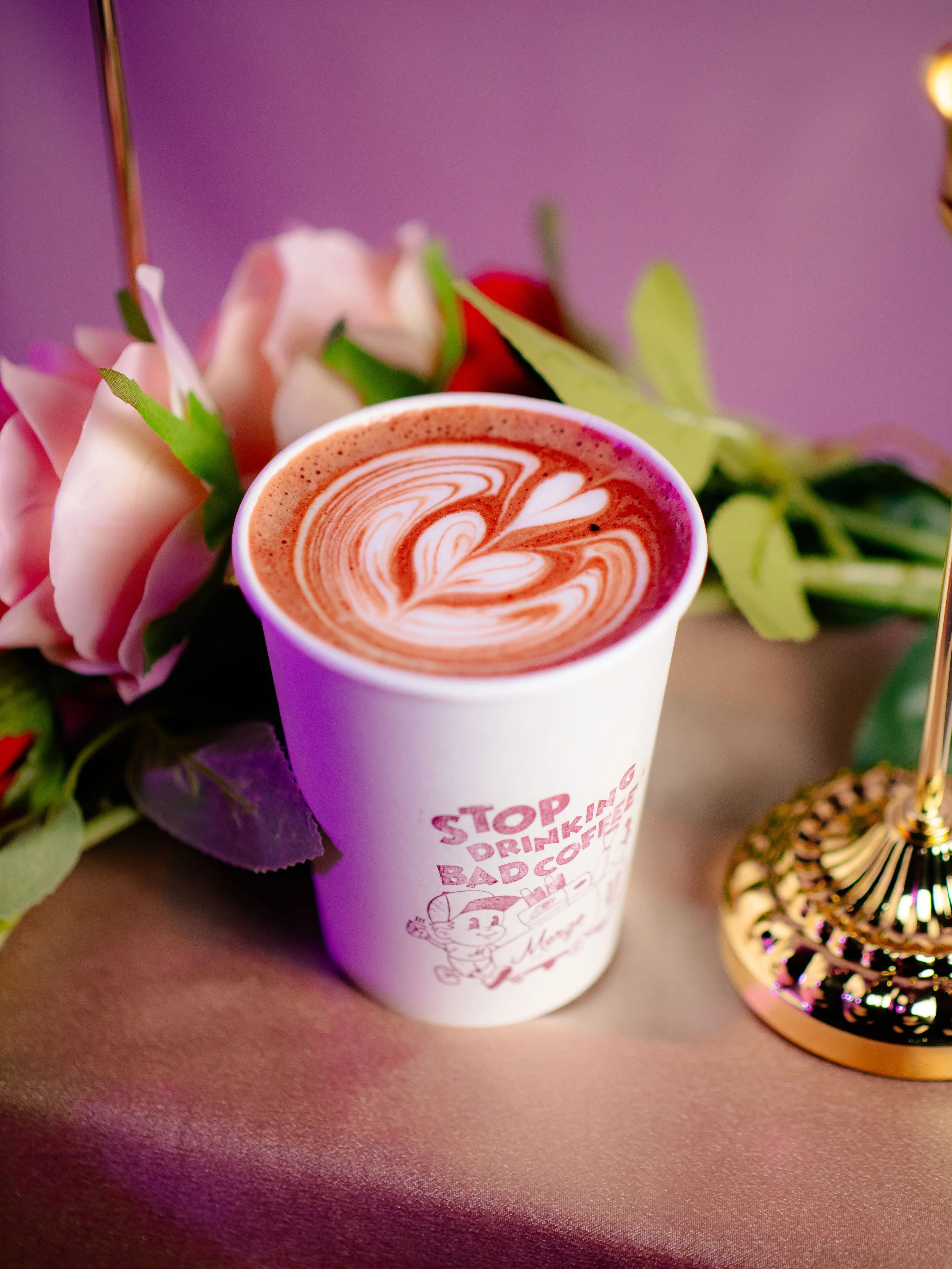 Latte with heart latte art surrounded by roses — small-batch roaster coffee and house-made syrups for Nashville weddings