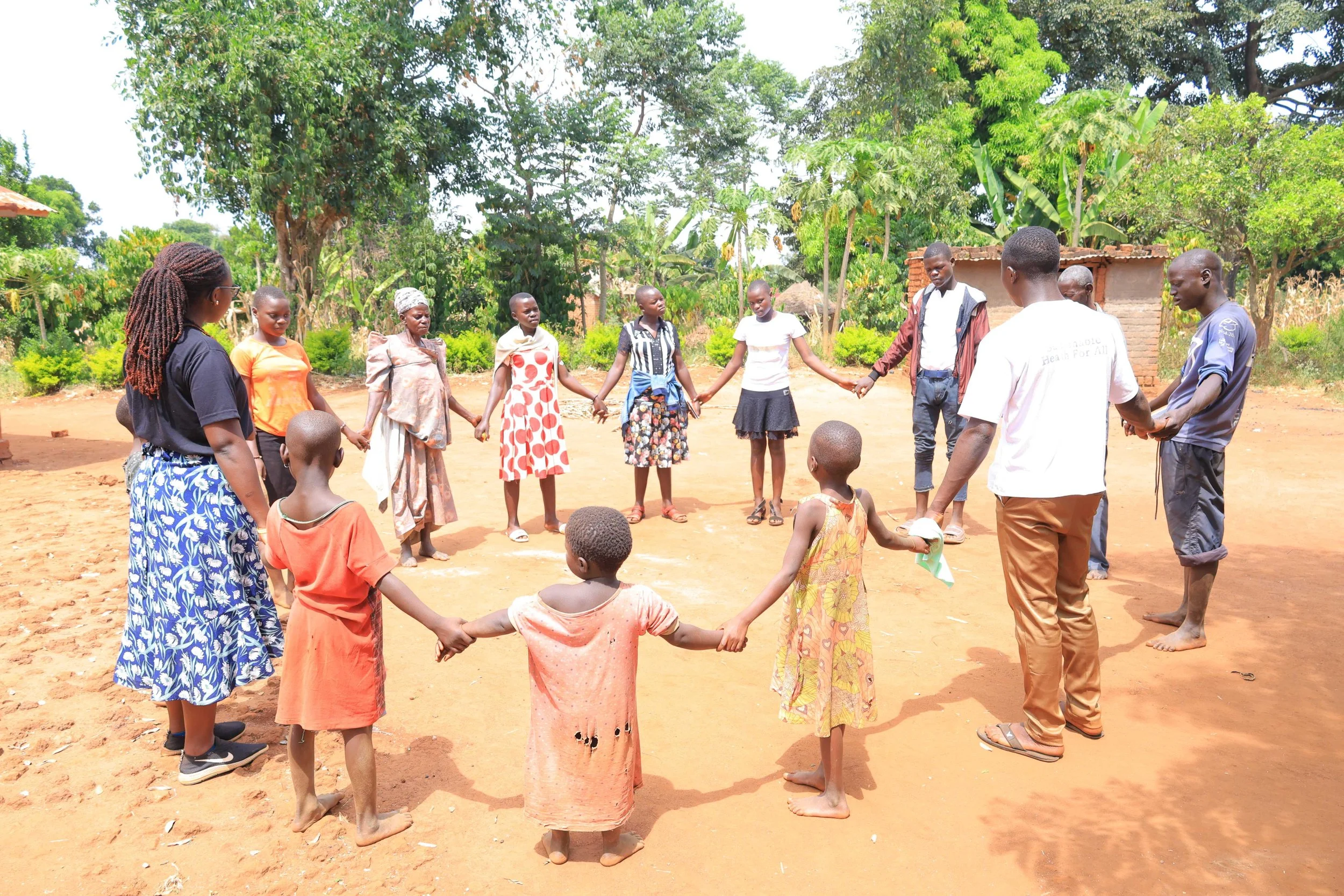 Students and teachers hold hands in a rural Eastern Ugandan village during an education session