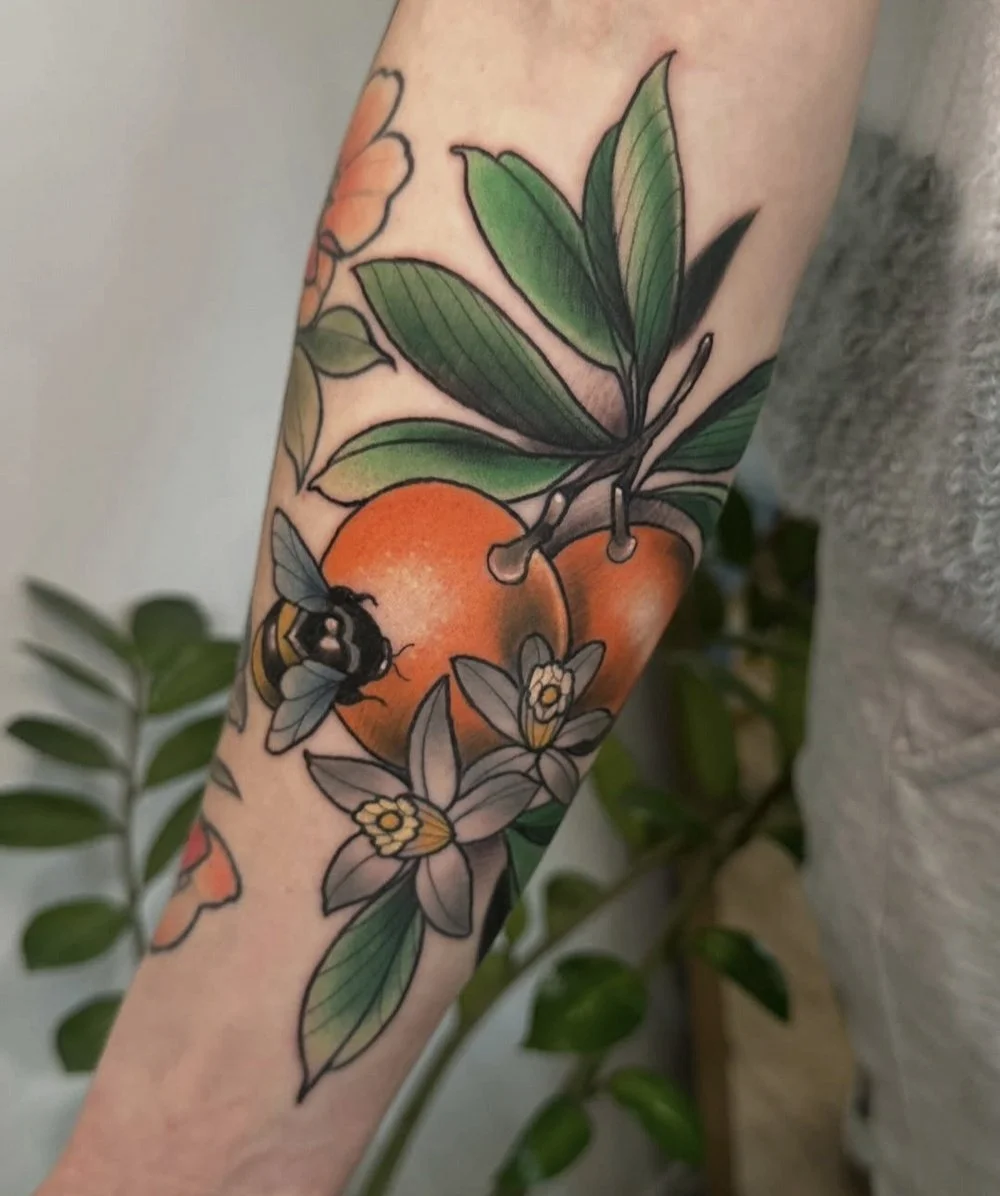 close up of tattoo with bees, oranges, and flowers