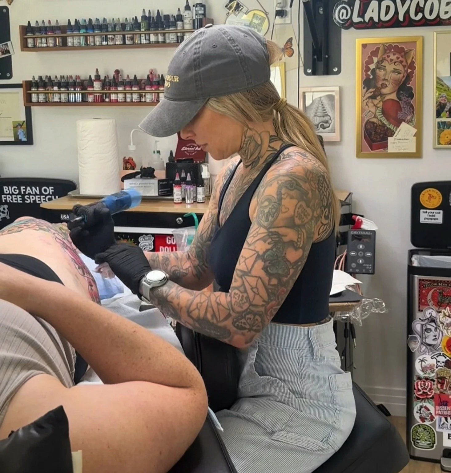 tattoo artist working on client leg