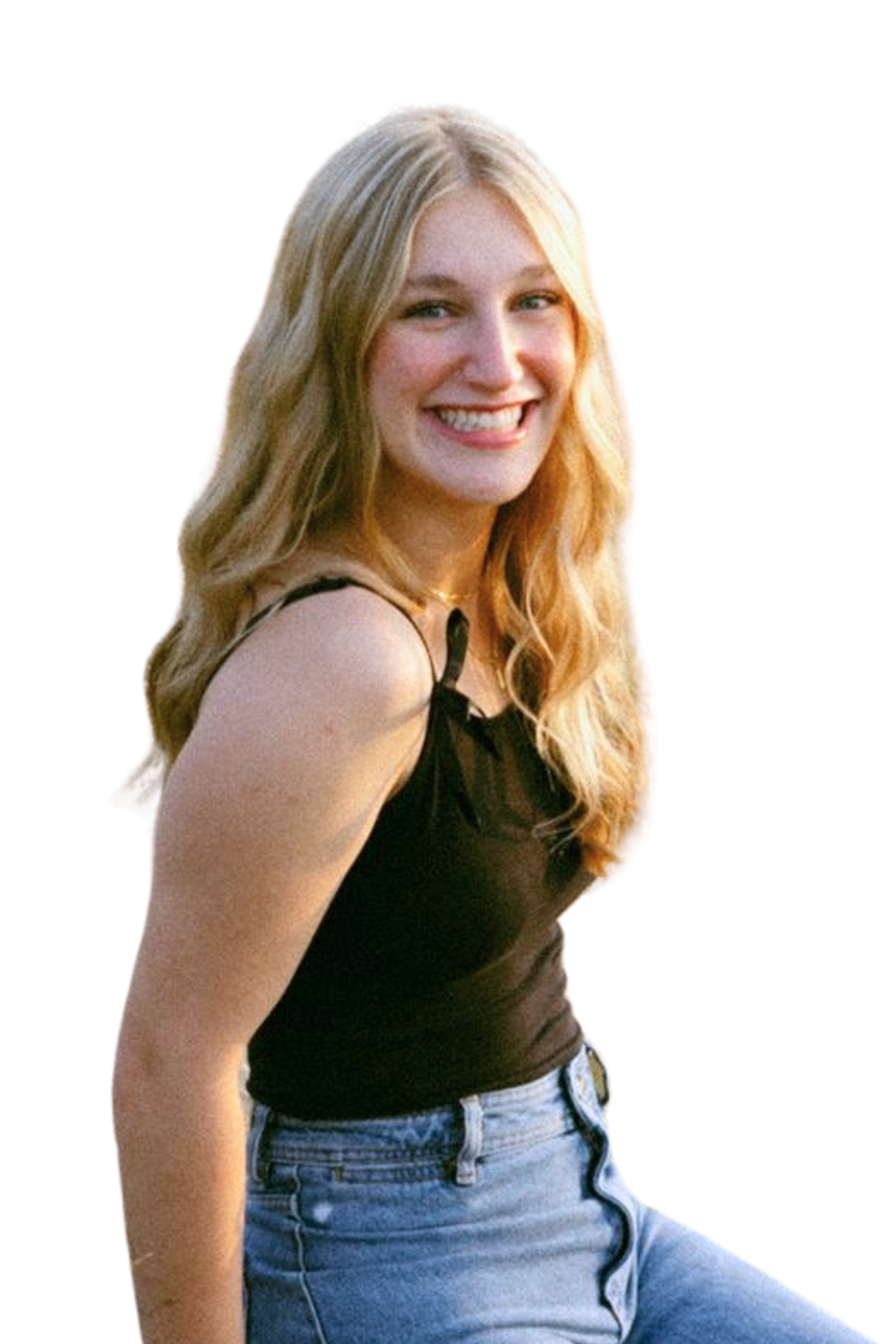 A young woman with long blonde hair, smiling, wearing a black sleeveless top and blue jeans, standing against a white background.