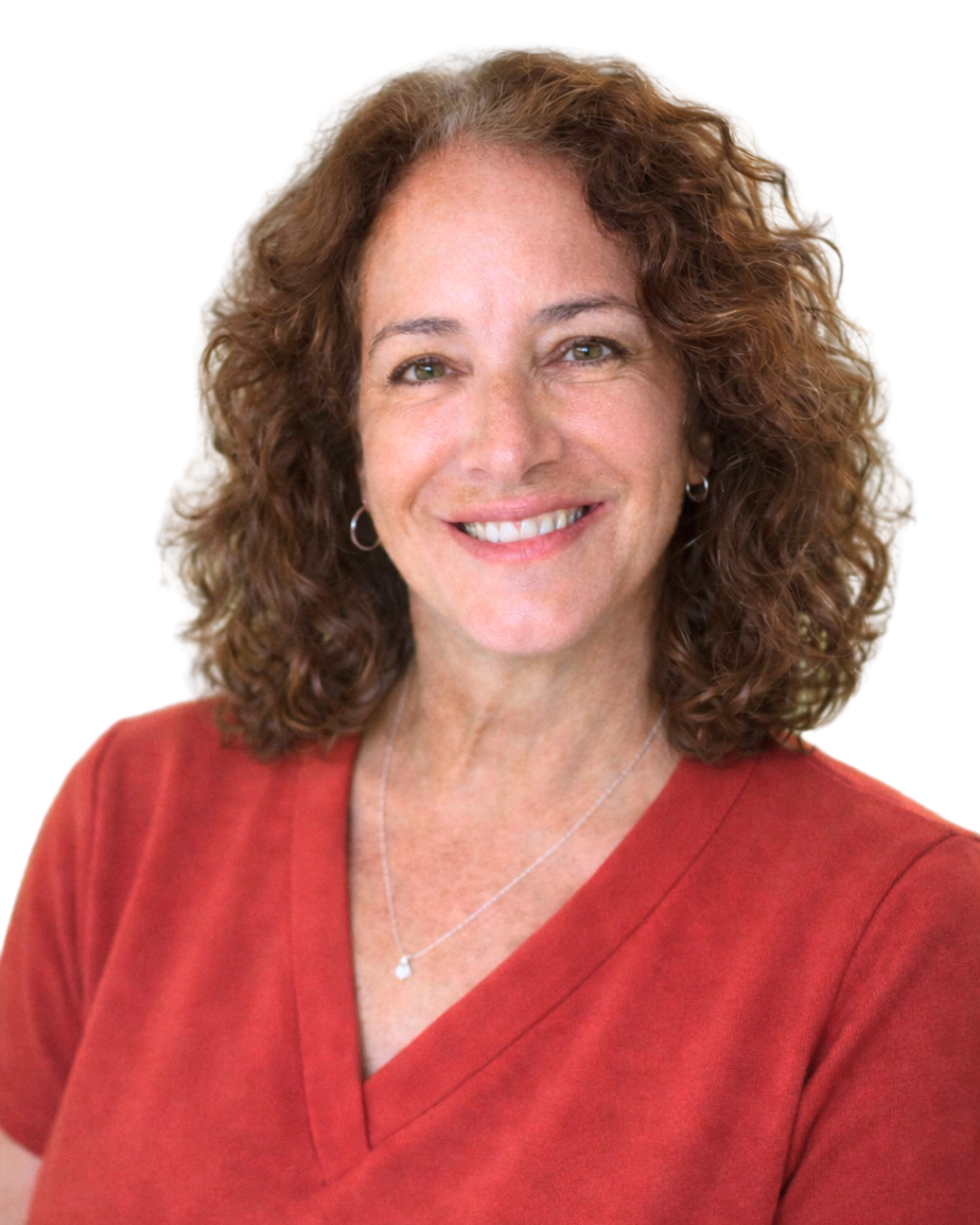 A smiling woman with curly reddish-brown hair, wearing a red top, a silver necklace, and small hoop earrings, against a white background.