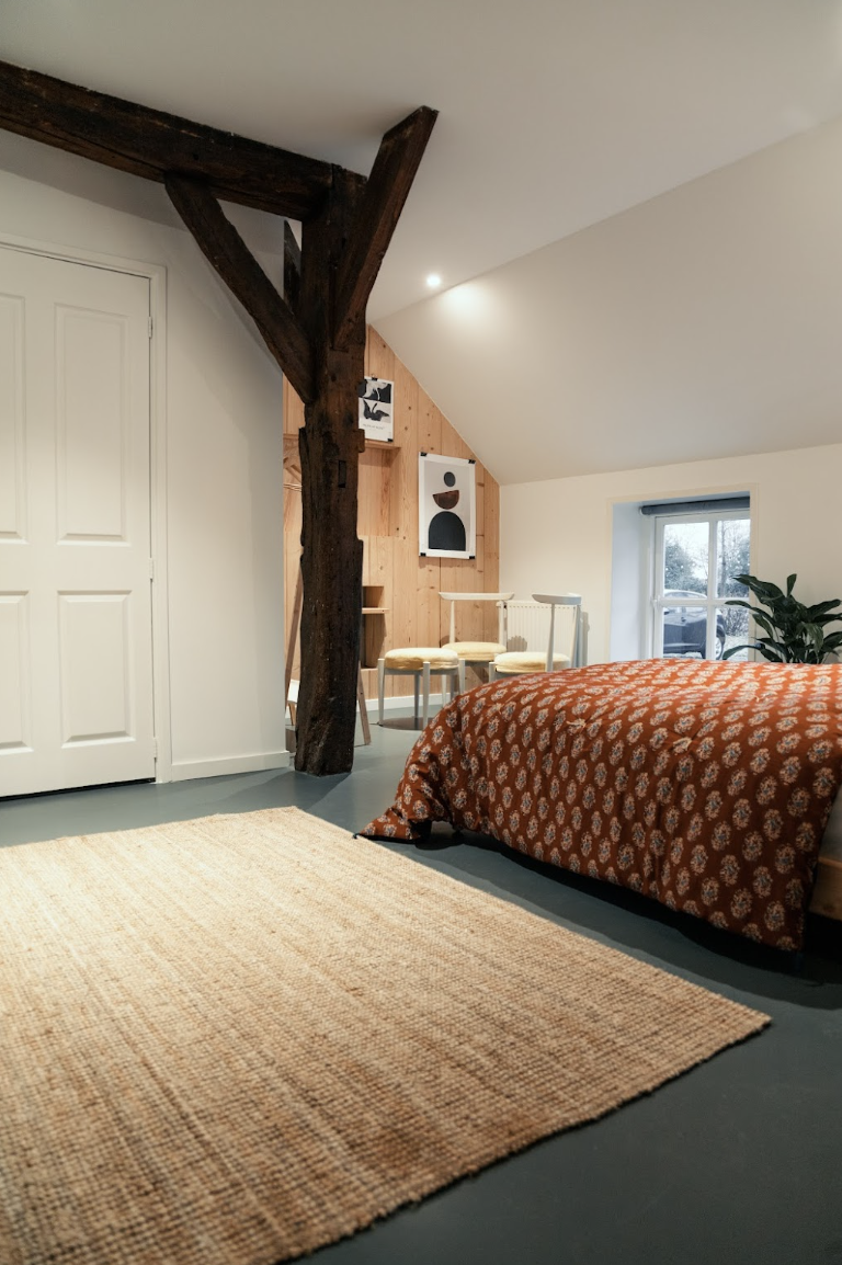 Farmhouse retreat bedroom with natural wooden floors and soft natural light, facilitator studio accommodation