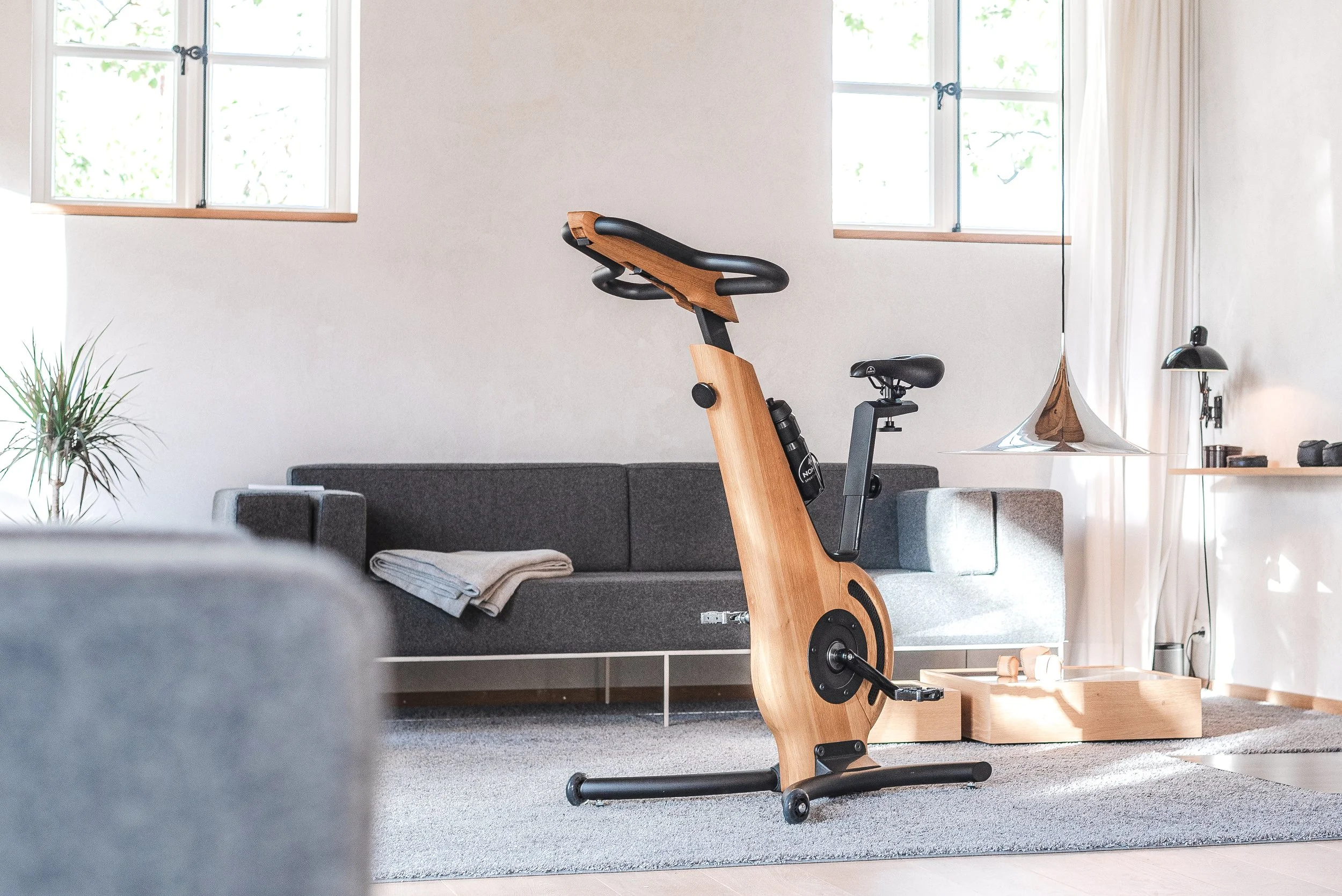 Holz Heimtrainer in einem stilvollen Wohnzimmer mit grauem Sofa und moderner Einrichtung.