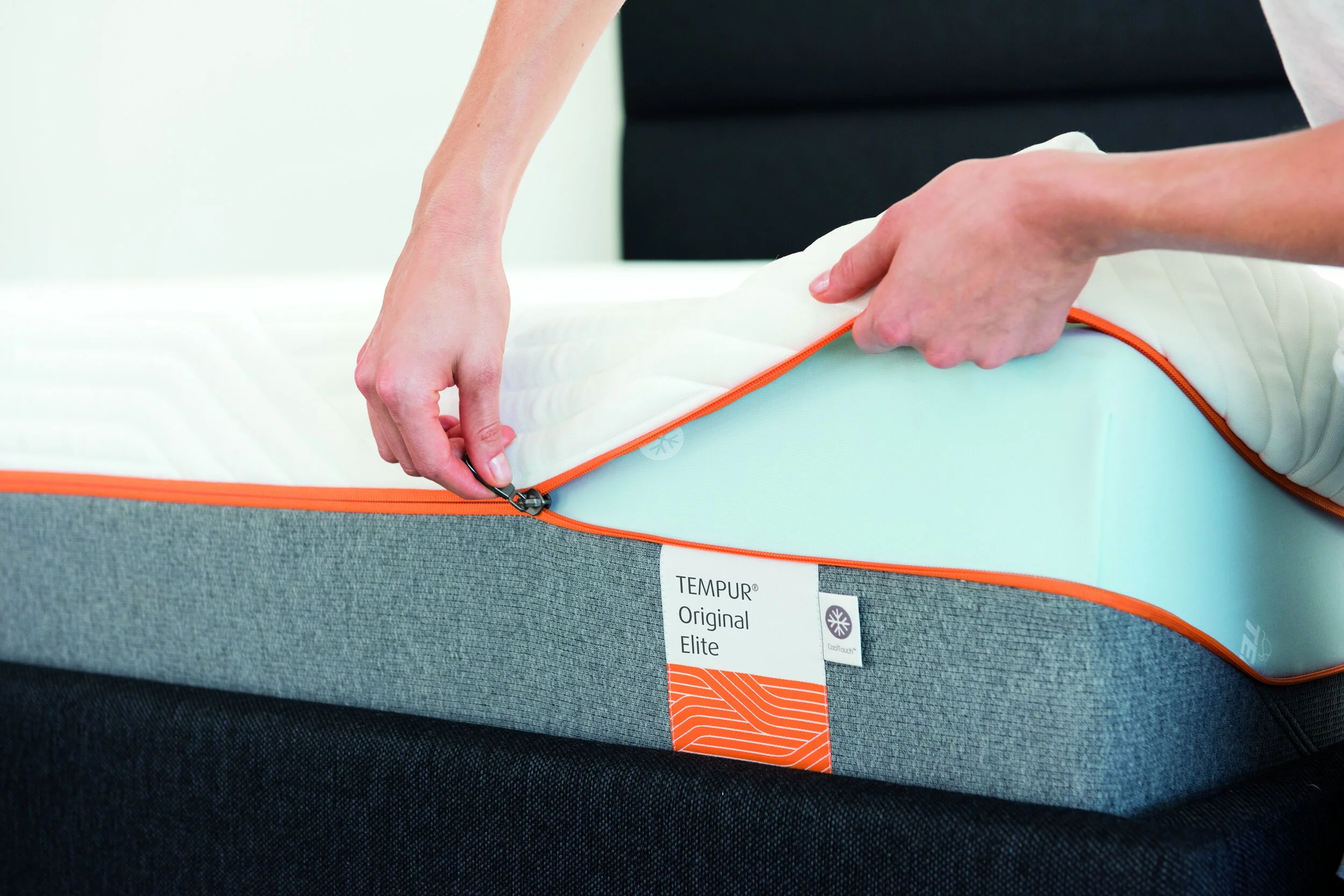 Person öffnet Reißverschluss eines Matratzenbezugs, darunter eine Tempur-Matratze sichtbar.