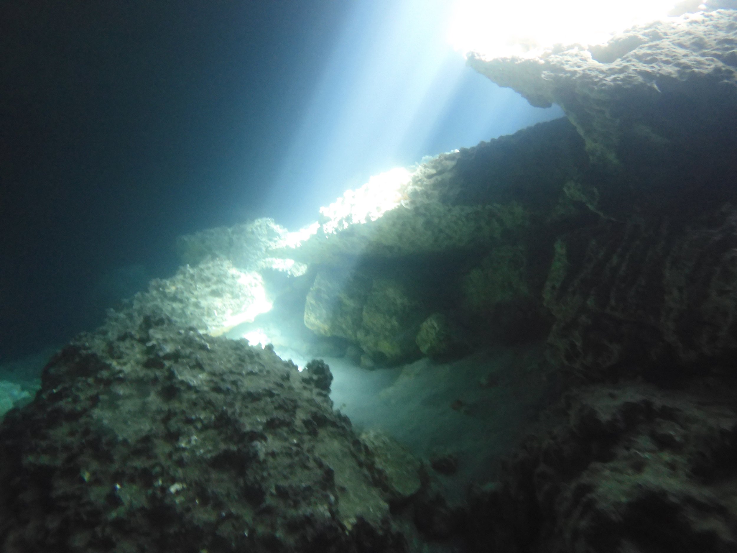 Underwater scene with rocks and sunlight streaming through the water.