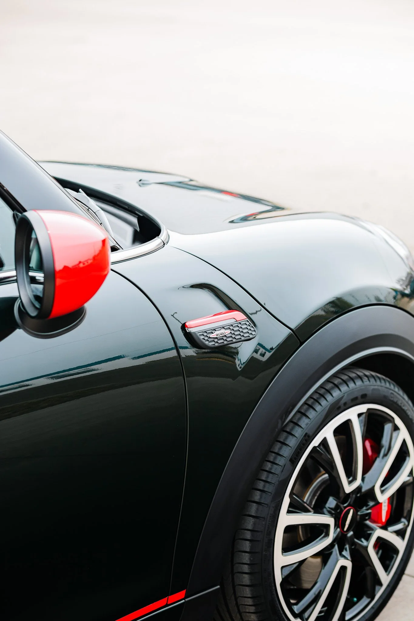 Close-up of a black sports car with red vinyl accents, showcasing the hood and fenders with paint protection film and ceramic coating in Hanna, Alberta.