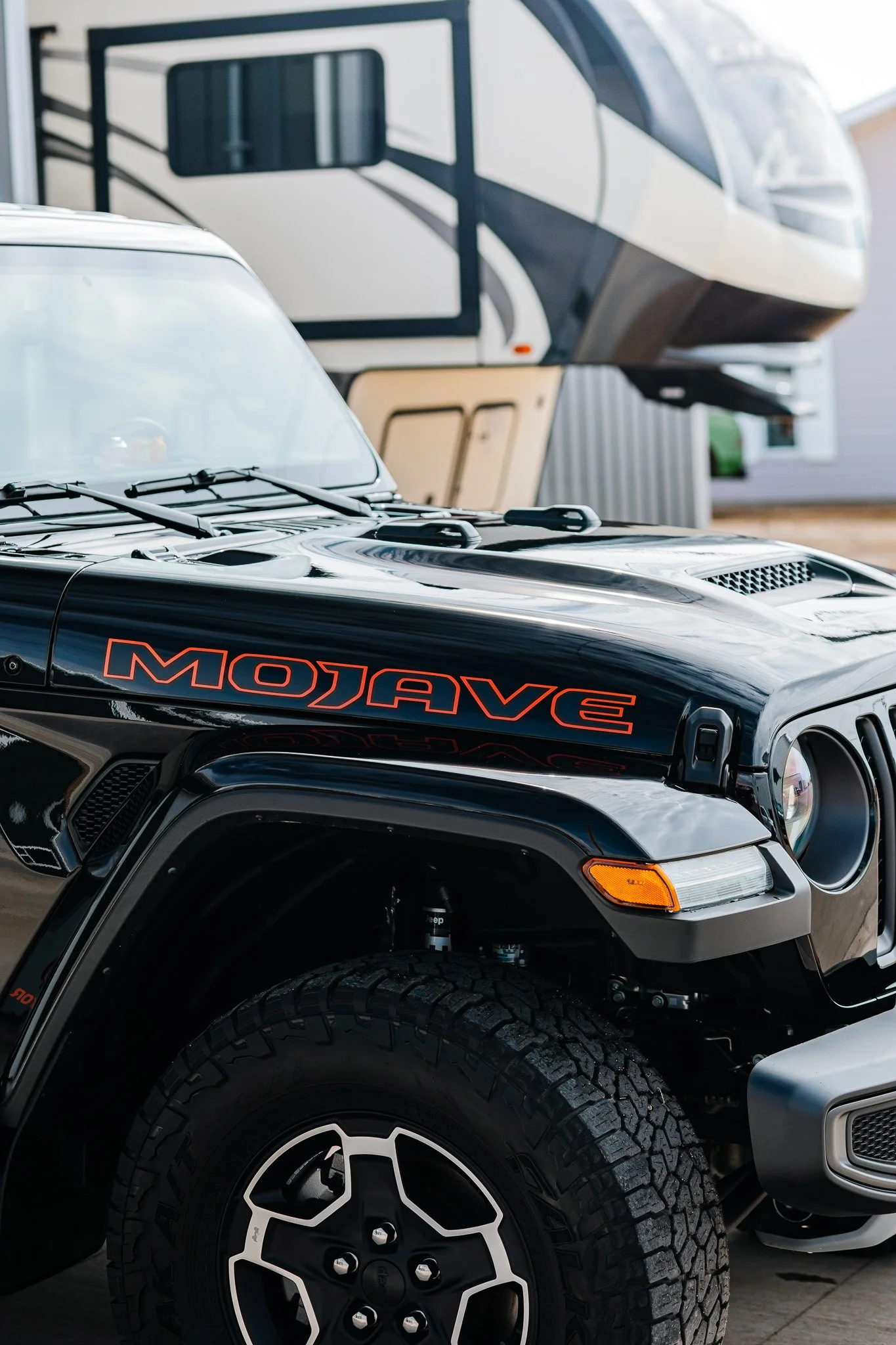 Close-up of a polished black Jeep Wrangler with red 'Mojave' decal, parked outdoors in Hanna, Alberta.