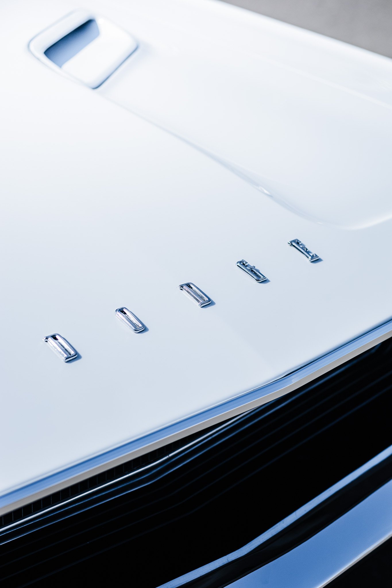 Close-up of a white Porsche car front with the Porsche logo in chrome letters in Hanna, Alberta.