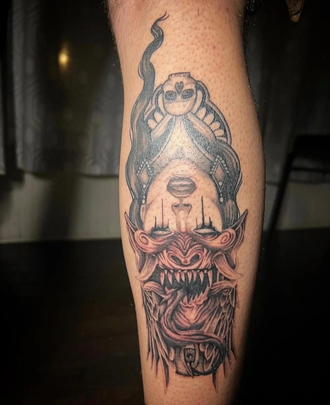 A black and grey realism tattoo of a girl head/face that switches to a demon/ monster face when viewed upside down on the back of a calf by portland tattoo artist at Upper Moon Tattoo, Daniel Aispuro