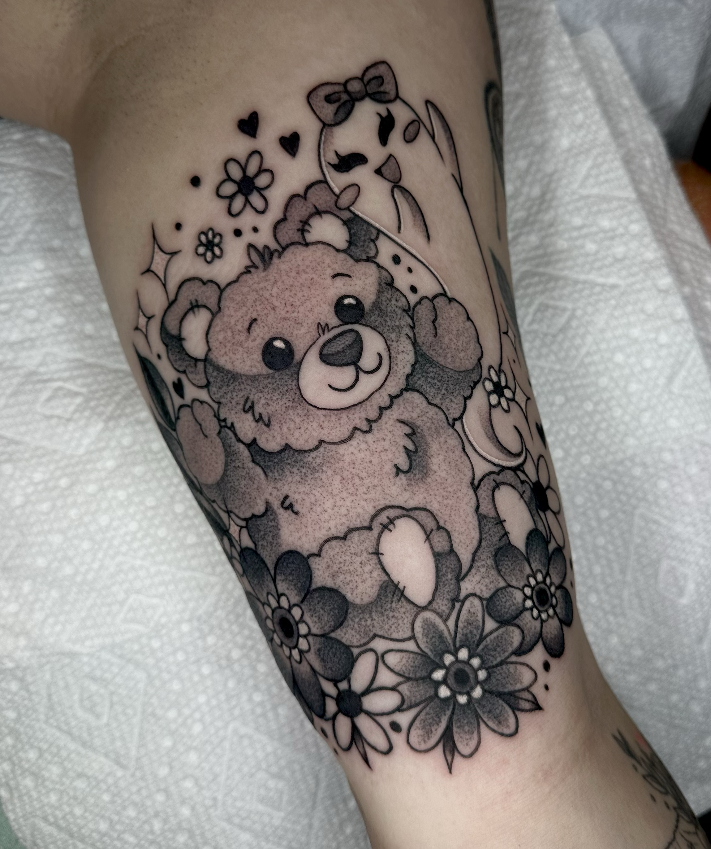 Cute fluffy teddy bear in black and grey tattoo with florals and a kawaii ghost on the inner arm  by Portland Tattoo artist at Upper Moon Tattoo Rae Syndulla 